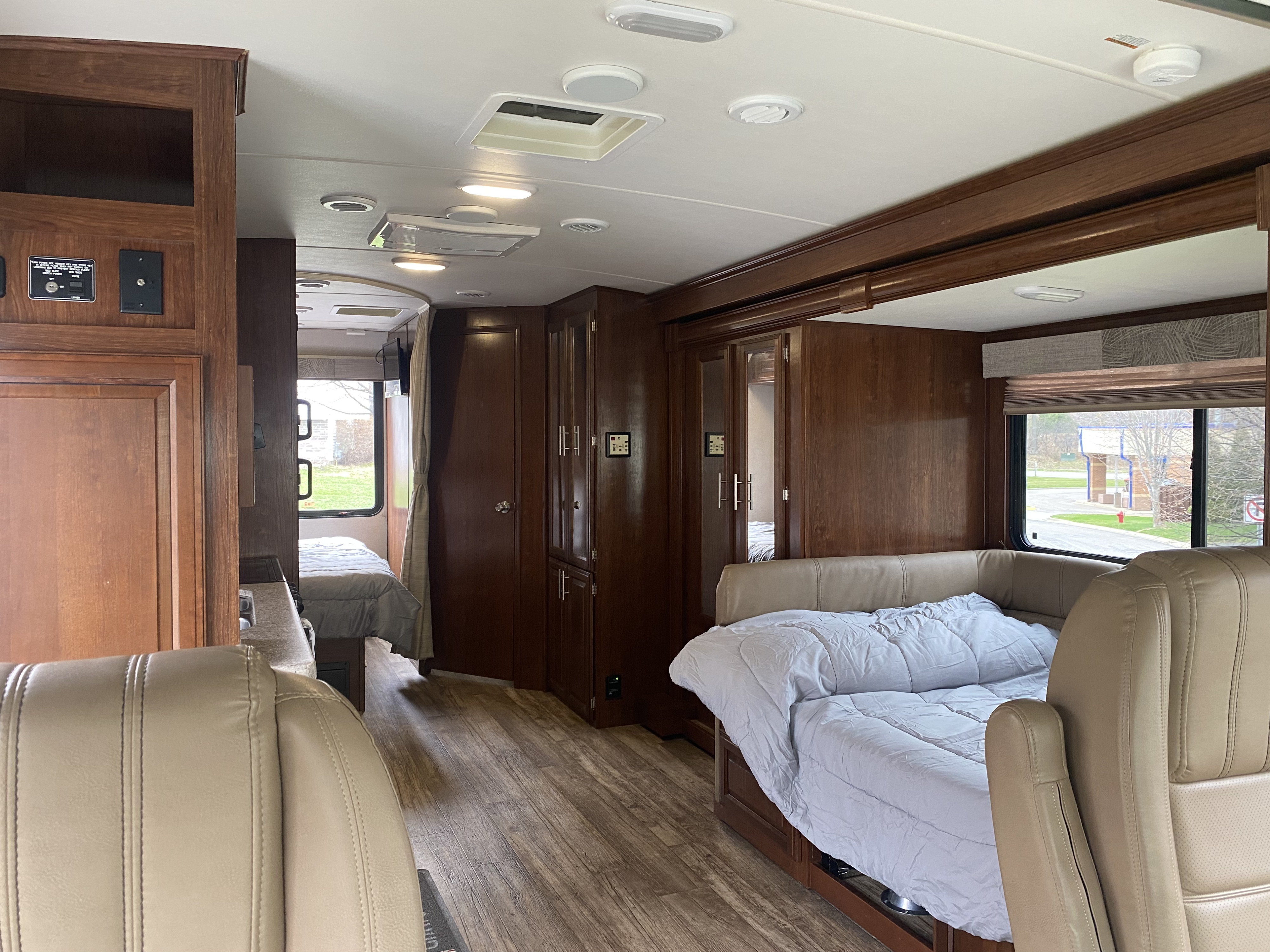 RV rental interior: detailed view of dark wood cabinetry, vinyl plank flooring, and light seating areas with bedroom & pull-out bed.. Forest River 23DS 2018