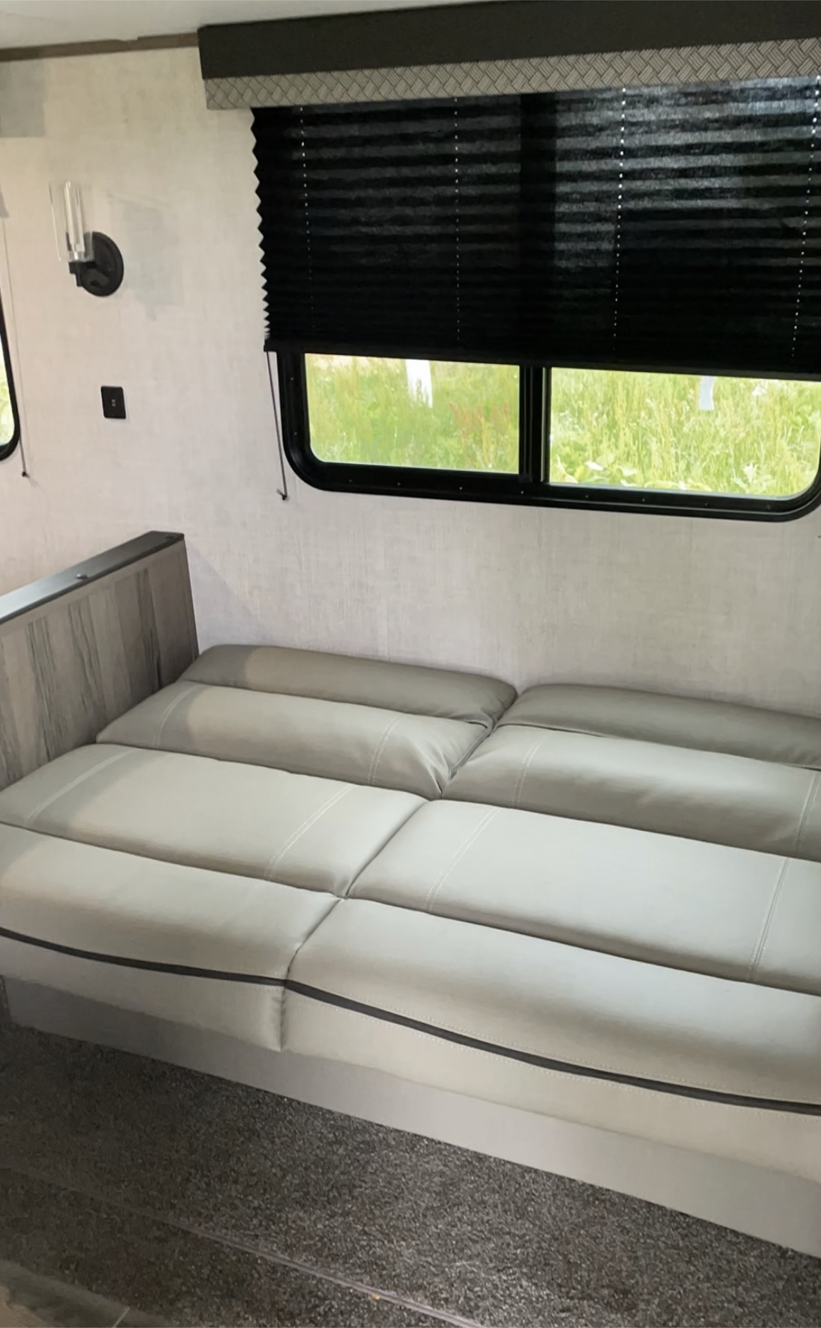 RV rental: Light gray convertible sofa bed, large windows with black pleated blinds, and wall sconce.. Gulf Stream Ameri Lite 279BH 2022