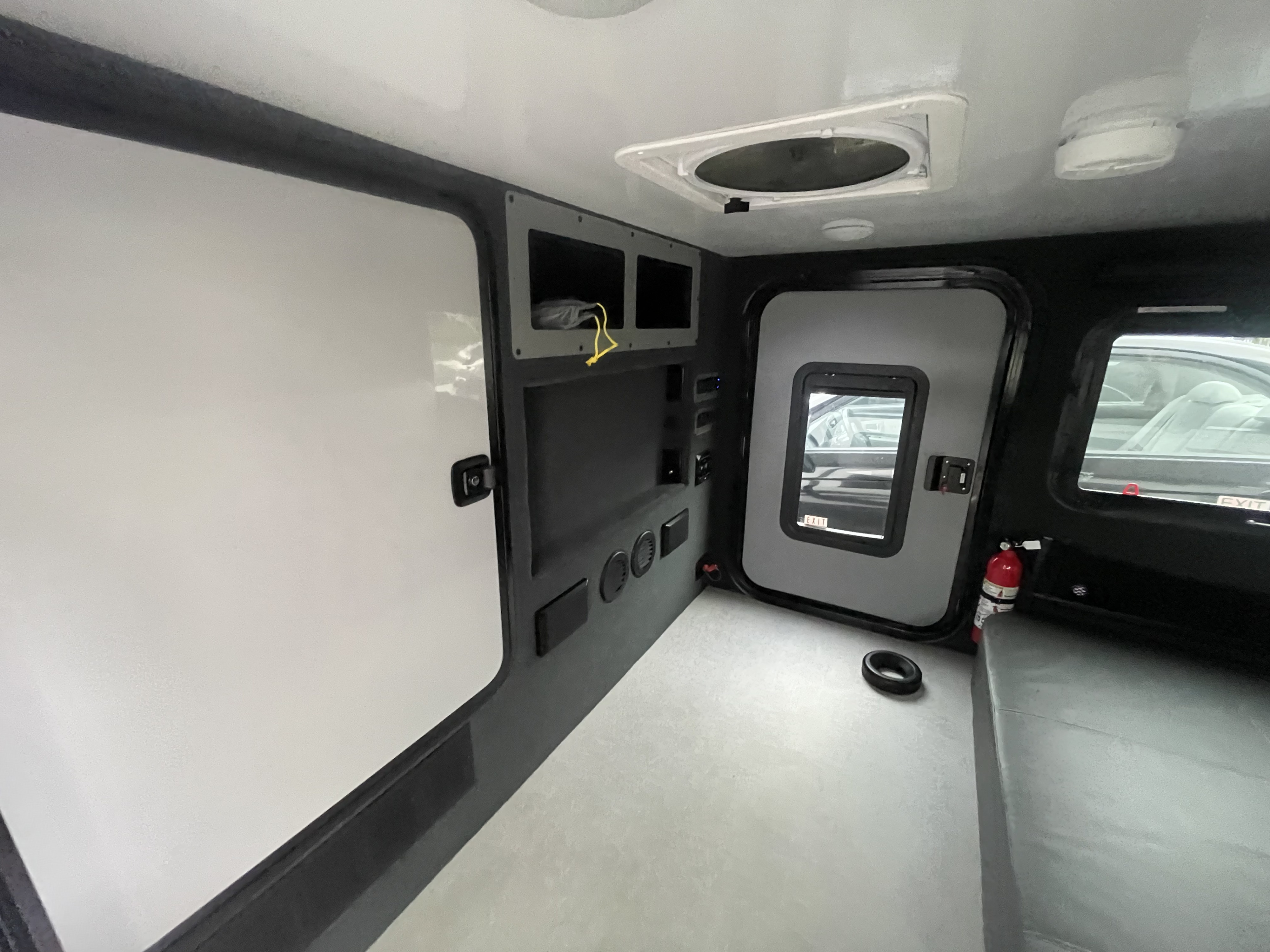 Interior of an RV rental, showcasing its functional design with ample storage, a side door, and ceiling vent.. Encore RV ROG 2022