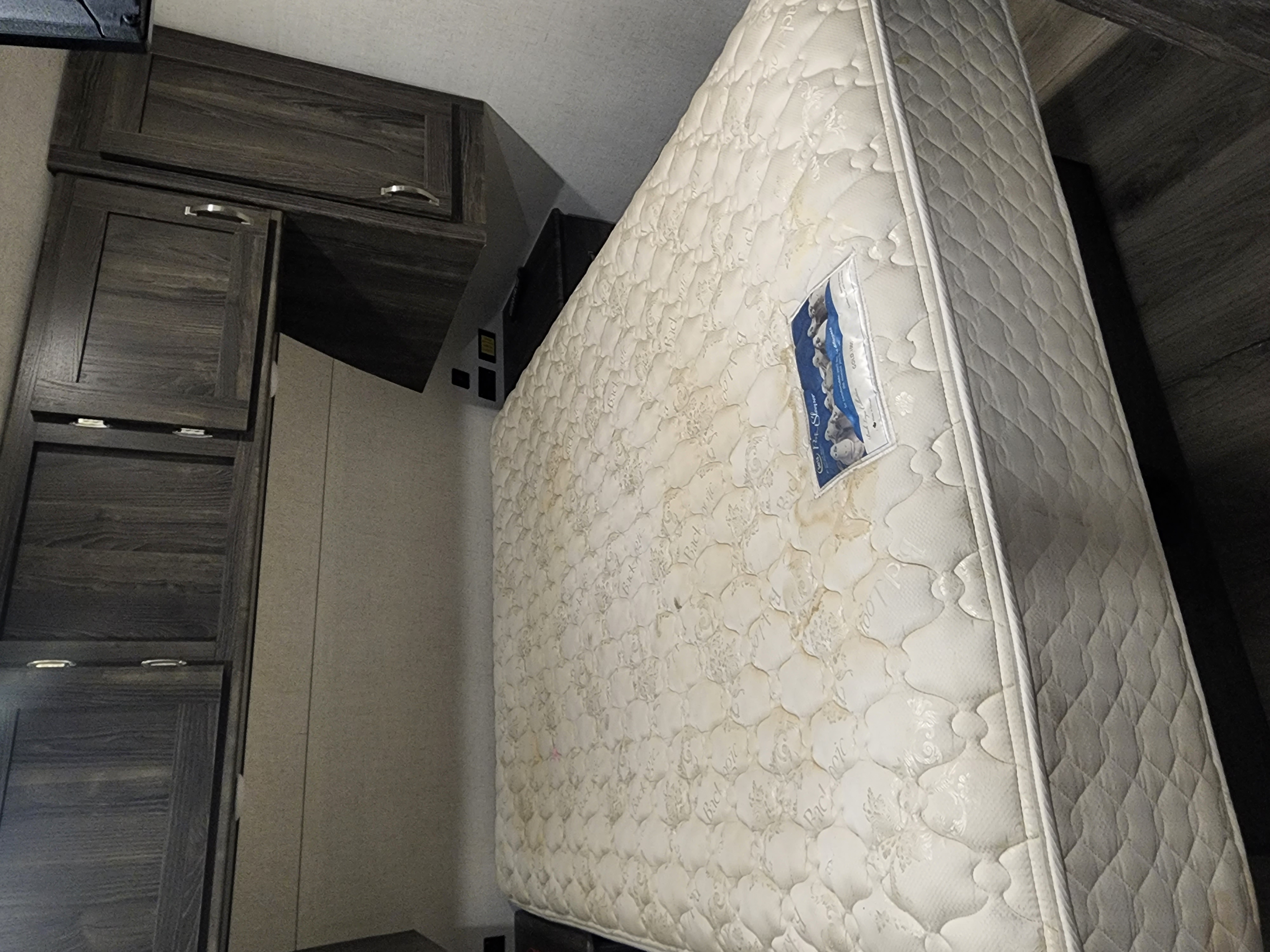 Stained mattress and wood cabinets in this RV rental's bedroom area.. Highland Ridge RV Open Range Ultra Lite 2019