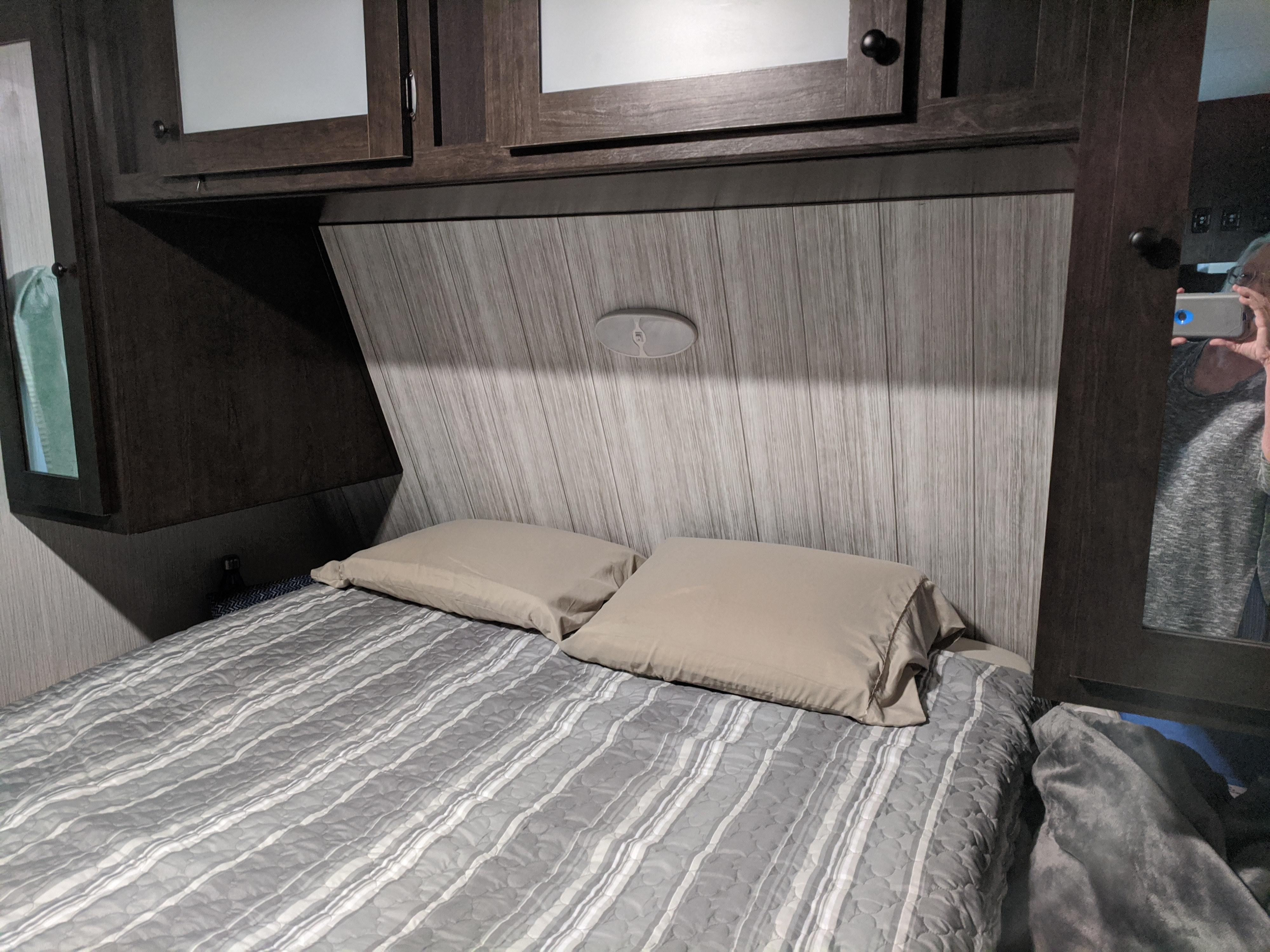 Cozy RV rental bedroom featuring modern overhead cabinets, a stylish headboard, and a comfortable bed with pillows.. Heartland RVs Pioneer 2020