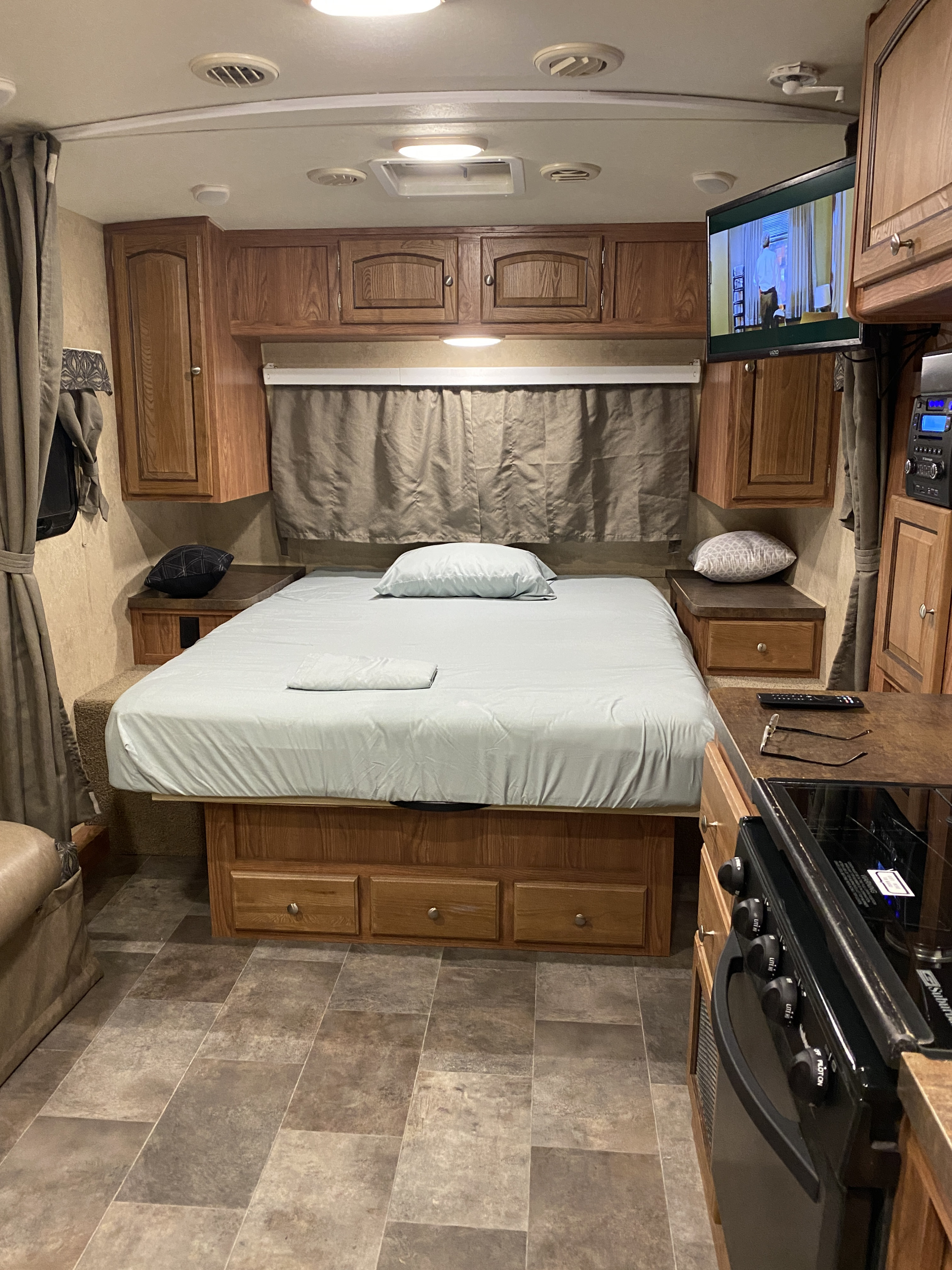 Compact RV rental interior featuring a cozy bedroom area with built-in storage and a peek at the kitchen appliances.. Forest River Micro-Lite 2015