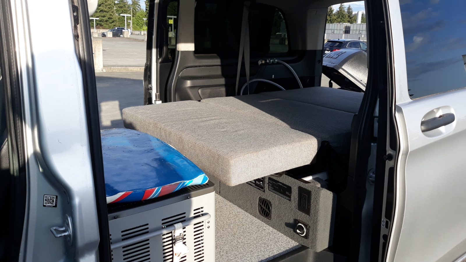 Explore this RV rental's compact camper van interior, featuring a cozy bed, portable fridge, and power station.. Mercedes Metris 2016