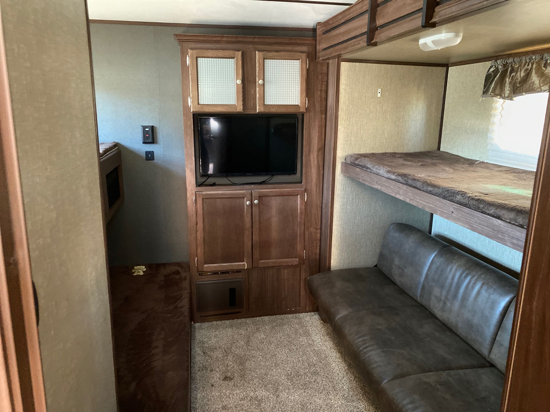 Spacious RV rental bunk room and entertainment center. Features multiple bunks, a sofa, and TV setup for comfortable travel.. Keystone RV Sprinter 2017