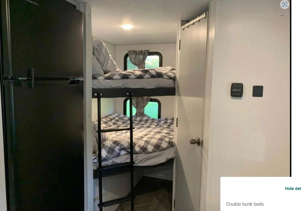 Cozy RV rental interior: a black refrigerator next to double bunk beds with checkered comforters, ladder, and windows.. Forest River Salem FSX 2021