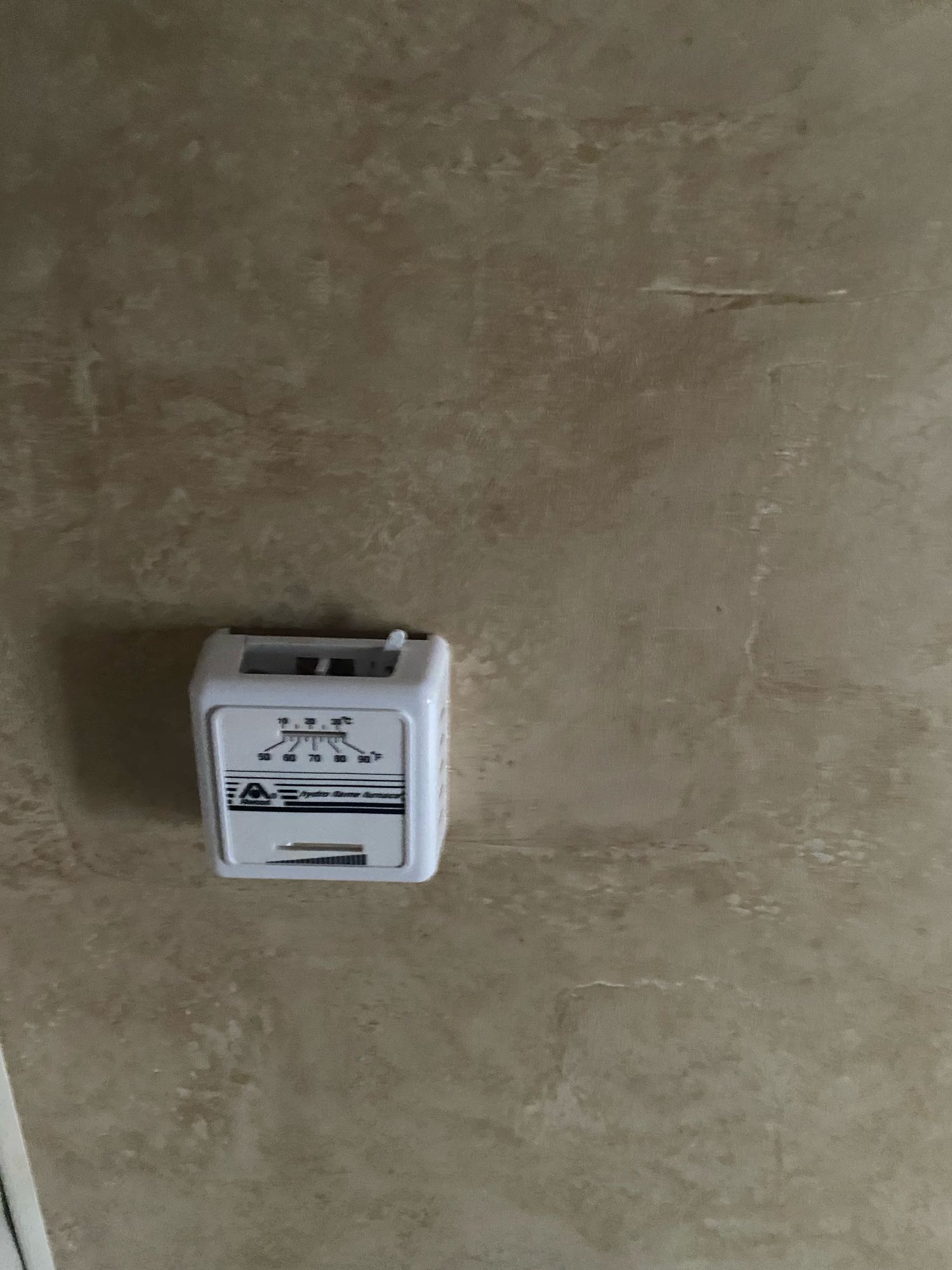 White thermostat on textured wall in RV rental, showing F/C temperature scales for HVAC control.. Jayco Jay Feather Ultra Lite 2012