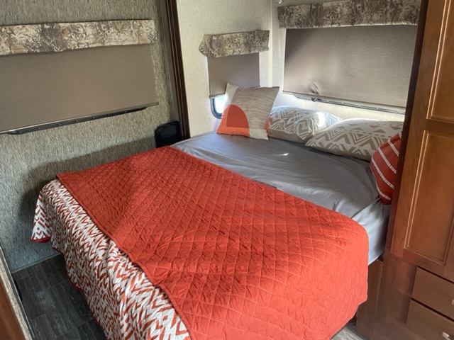 Inviting RV rental bedroom: cozy bed with orange quilt, patterned sheets, window blinds. Perfect for relaxing on the go.. Forester MBS 2018