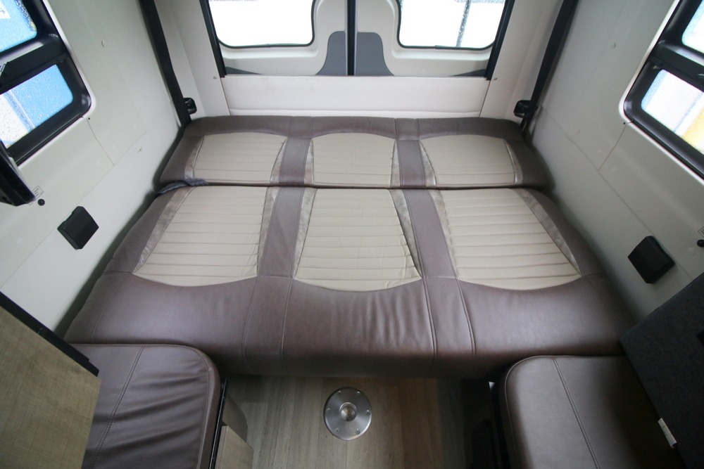 Inside this rv rental: A flexible bed/seating area with two-tone cushions, side windows, and a floor mount for a table.. Winnebago Era 2019
