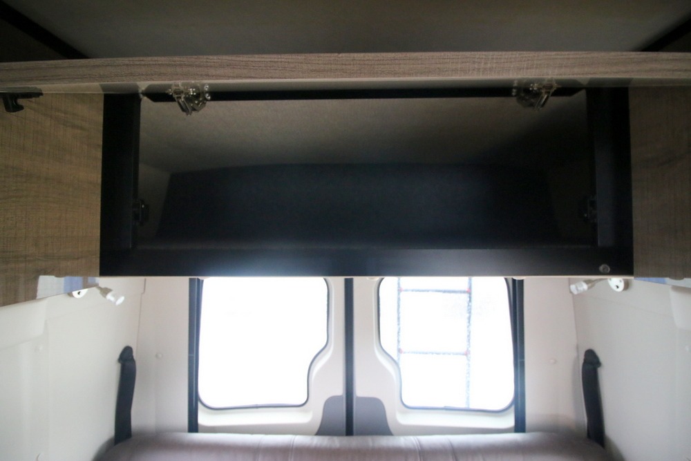 Explore this RV rental's interior: open overhead cabinet, bright rear windows, and a comfortable bench/bed for your journey.. Winnebago Era 2019