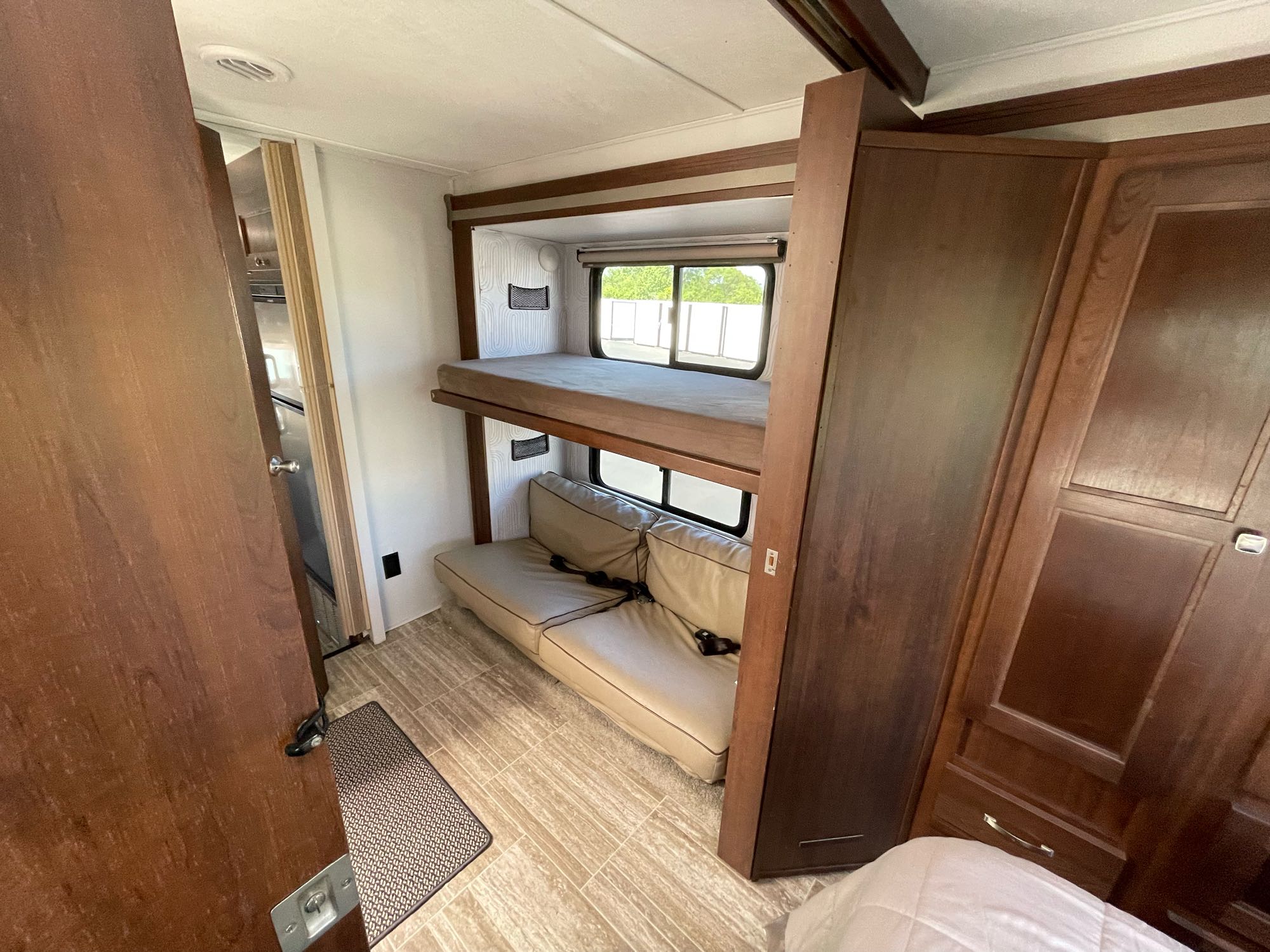 Spacious RV rental interior showcasing comfortable bunk beds, a convertible sofa, and dark wood cabinetry. Ideal for travel.. Forest River Sunseeker LE 2019