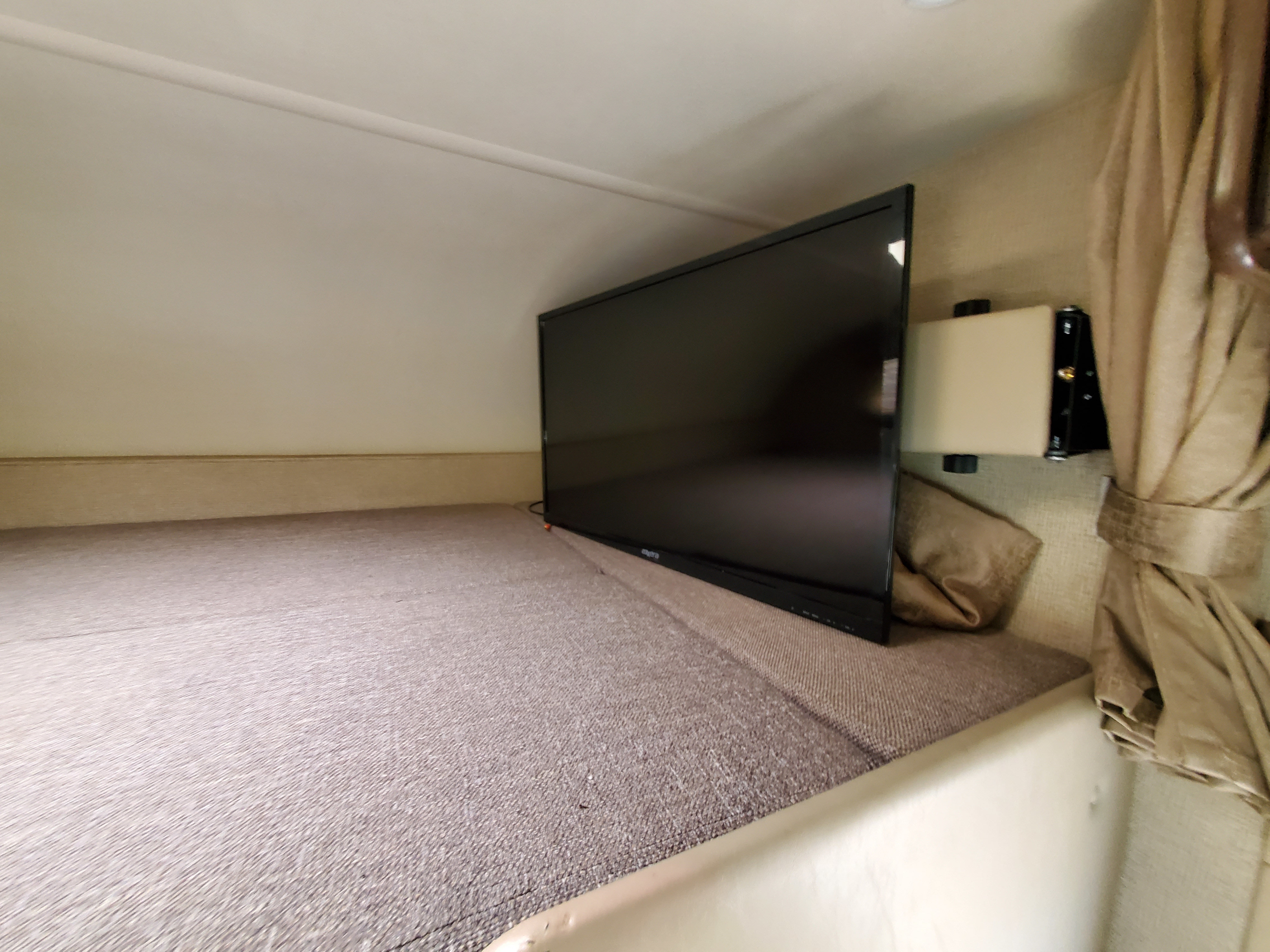 Explore RV rental comfort! This cozy cab-over bunk features a TV for entertainment and a soft sleeping area.. thor freedom elite 2019