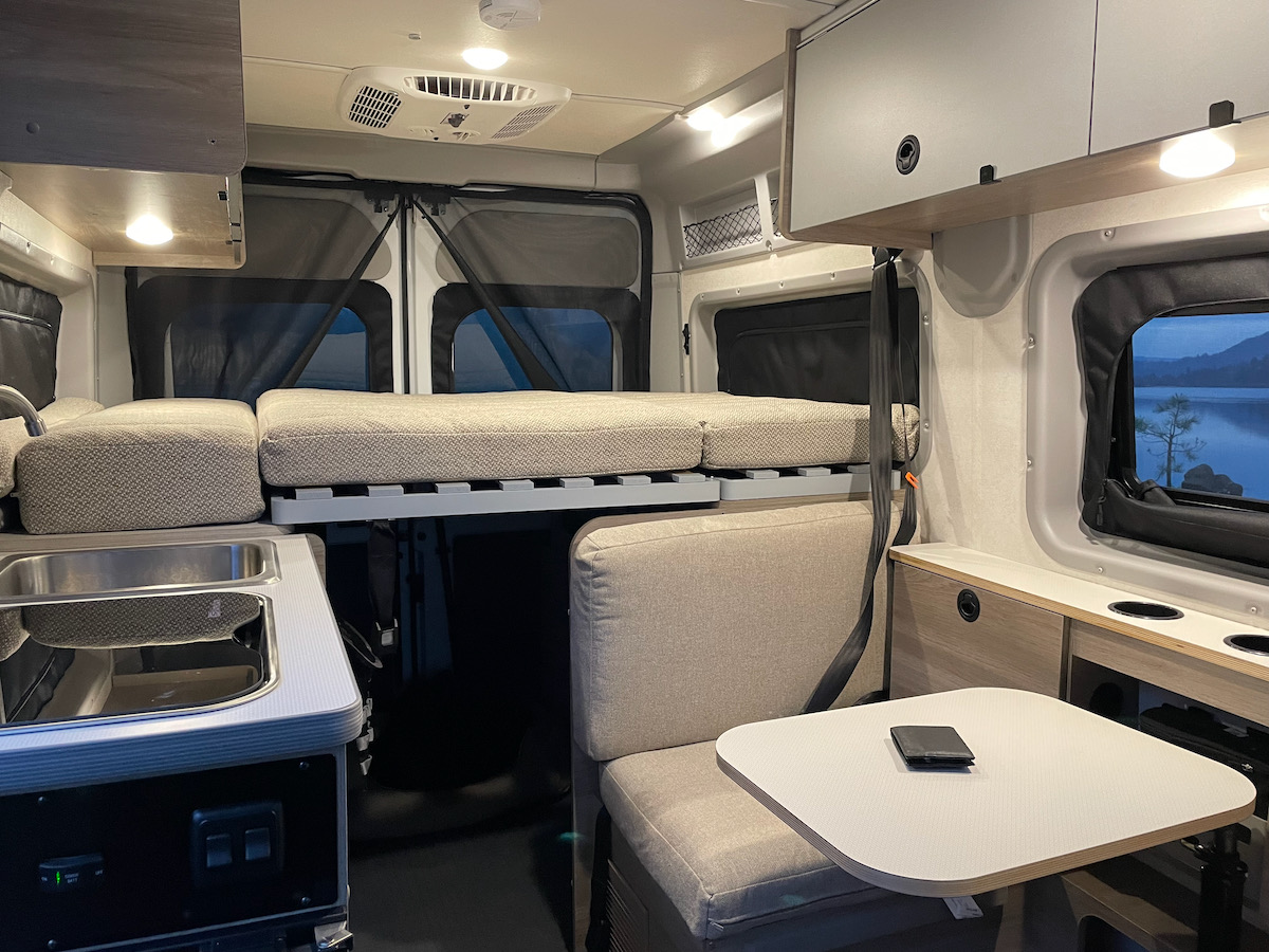 Cozy RV rental interior with convertible bed, kitchenette, and dining area. Perfect for travel adventures!. Winnebago pocket 2023