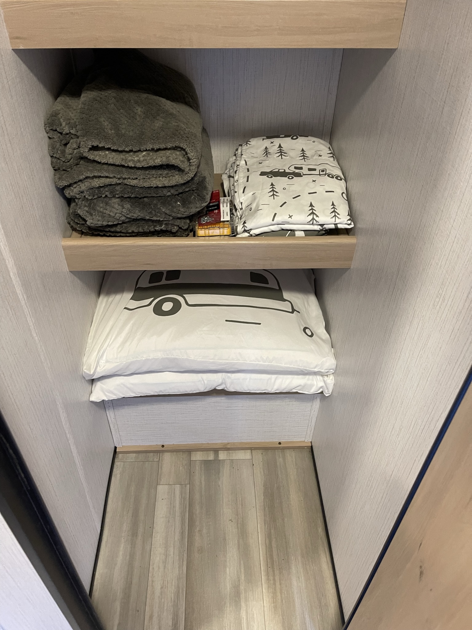 Organized RV rental storage: plush blankets & camper-themed pillows neatly tucked in a compact closet space.. Cruiser RV Radiance 2022