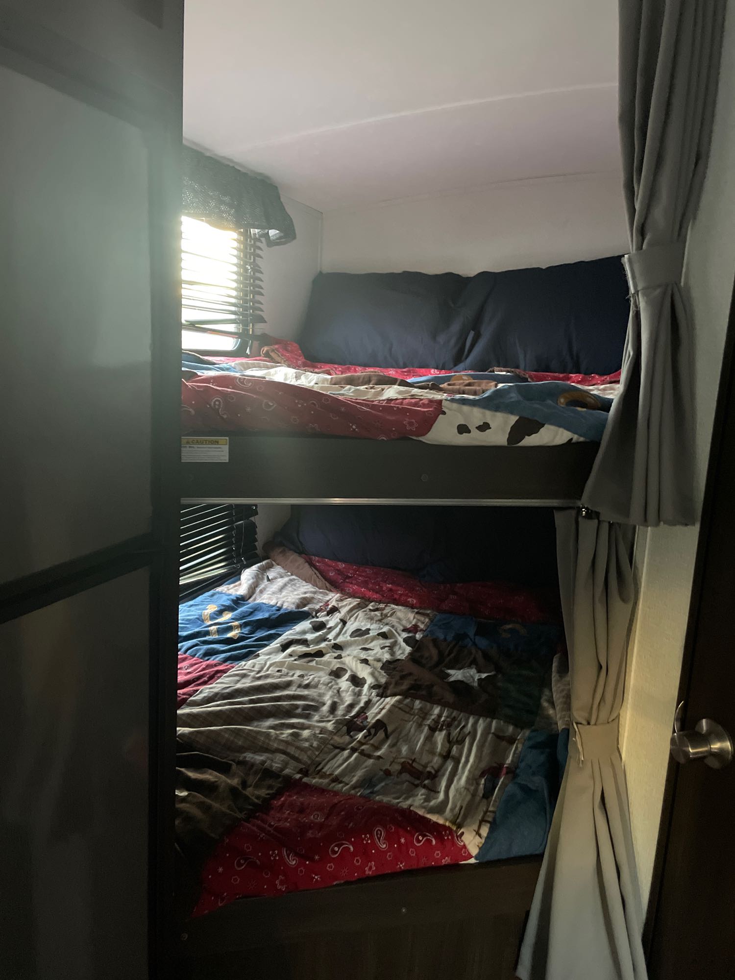 Inside an RV rental: two bunk beds with vibrant bedding and sunlight streaming through window blinds.. Keystone Springdale 2020