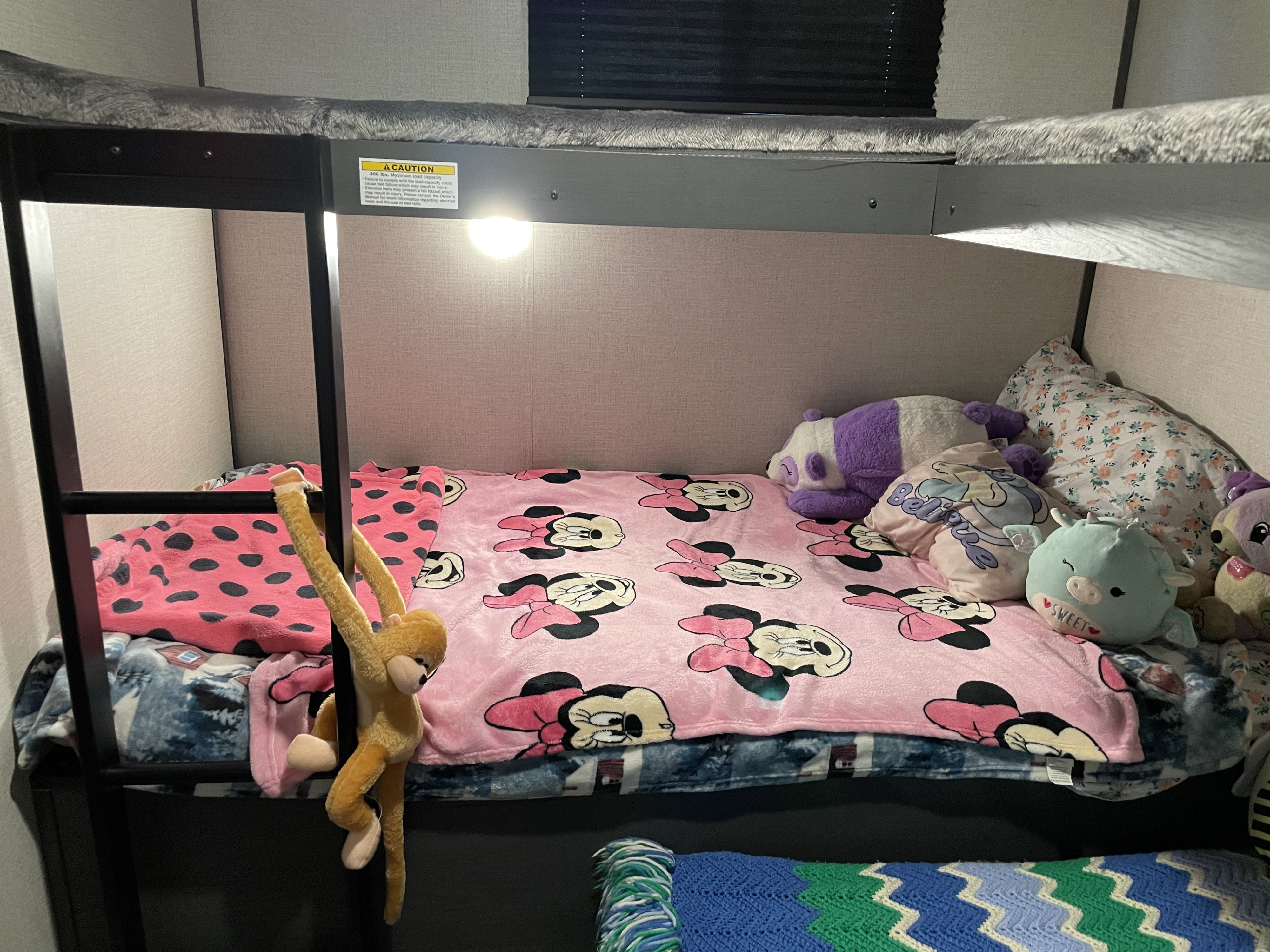 RV rental bunk beds with colorful kids' bedding, stuffed animals, and a fun monkey toy. Cozy mobile living.. Dutchman Colorado 2022
