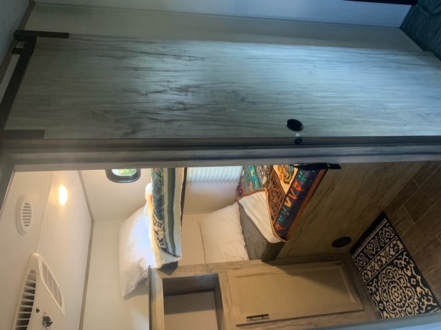 Inside an RV rental: a compact sleeping area with bunk beds, wooden cabinetry, and an AC unit for comfort.. Forest River Cherokee Alpha Wolf 2022