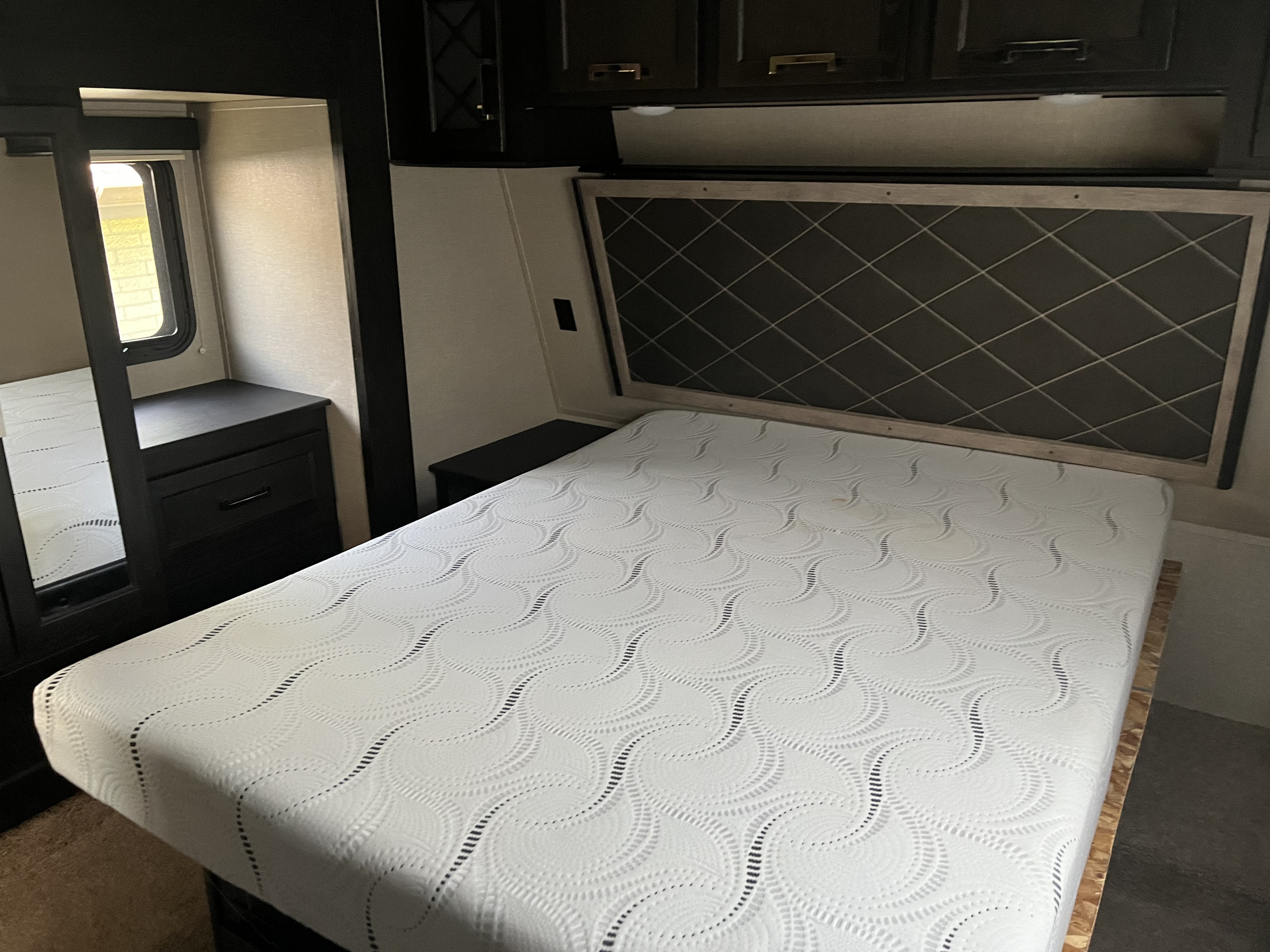 RV rental bedroom featuring a clean mattress, diamond-pattern headboard, and convenient storage cabinets.. Keystone Fuzion 2018