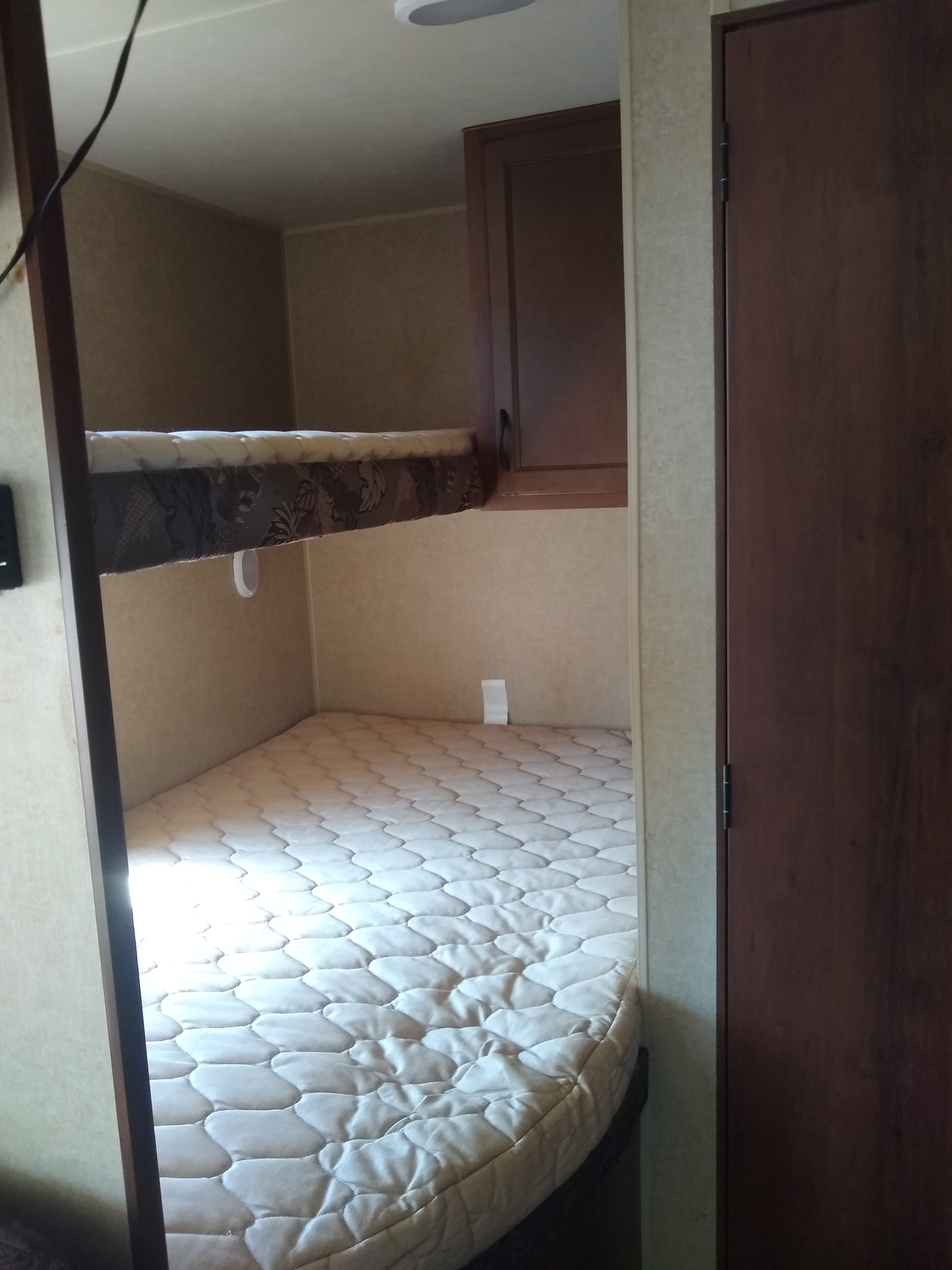 Cozy RV rental bunk beds, featuring upper and lower mattresses in a compact interior with a storage cabinet and door.. Jayco Jay Flight 26BH 2014