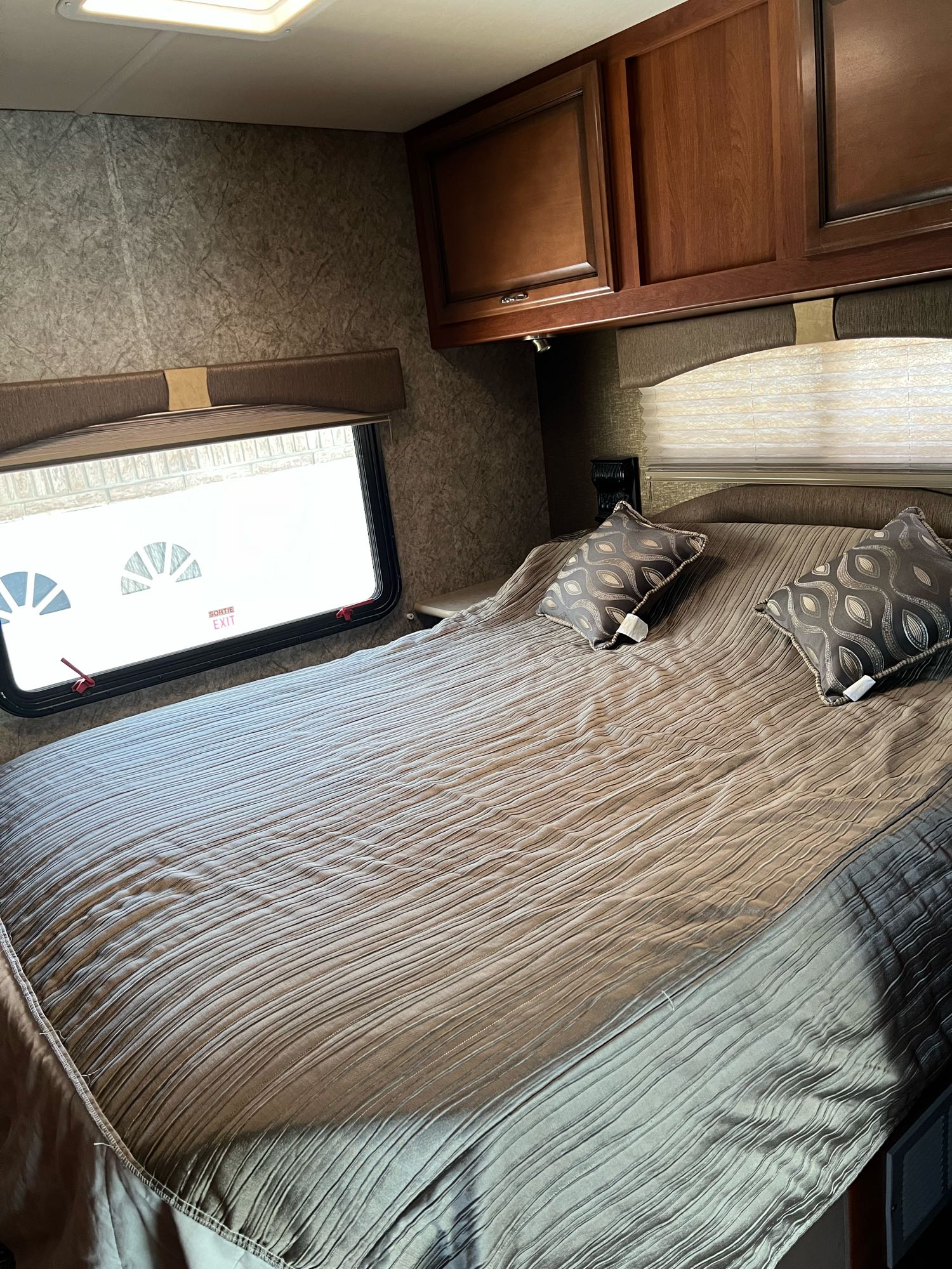 RV rental bedroom interior, showcasing a comfortable bed, overhead cabinets, and a window for a cozy stay.. Fleetwood Other 2015