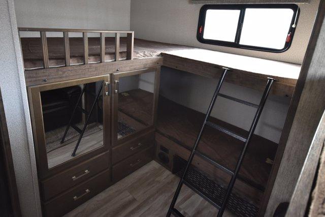 RV rental interior: cozy bunk beds with a ladder, a window, and ample storage cabinets below, perfect for family travel.. Grand Design Solitude 2020