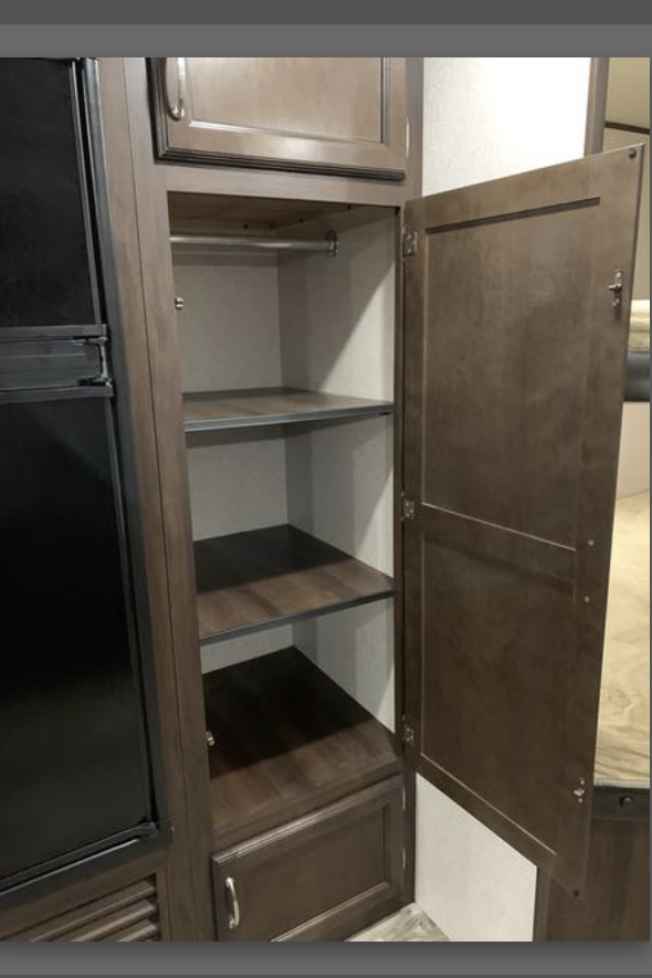 RV rental interior featuring a versatile storage cabinet with shelves, hanging rod, and drawer, next to a refrigerator.. Jayco Jay Flight SLX Baja Edition 2017