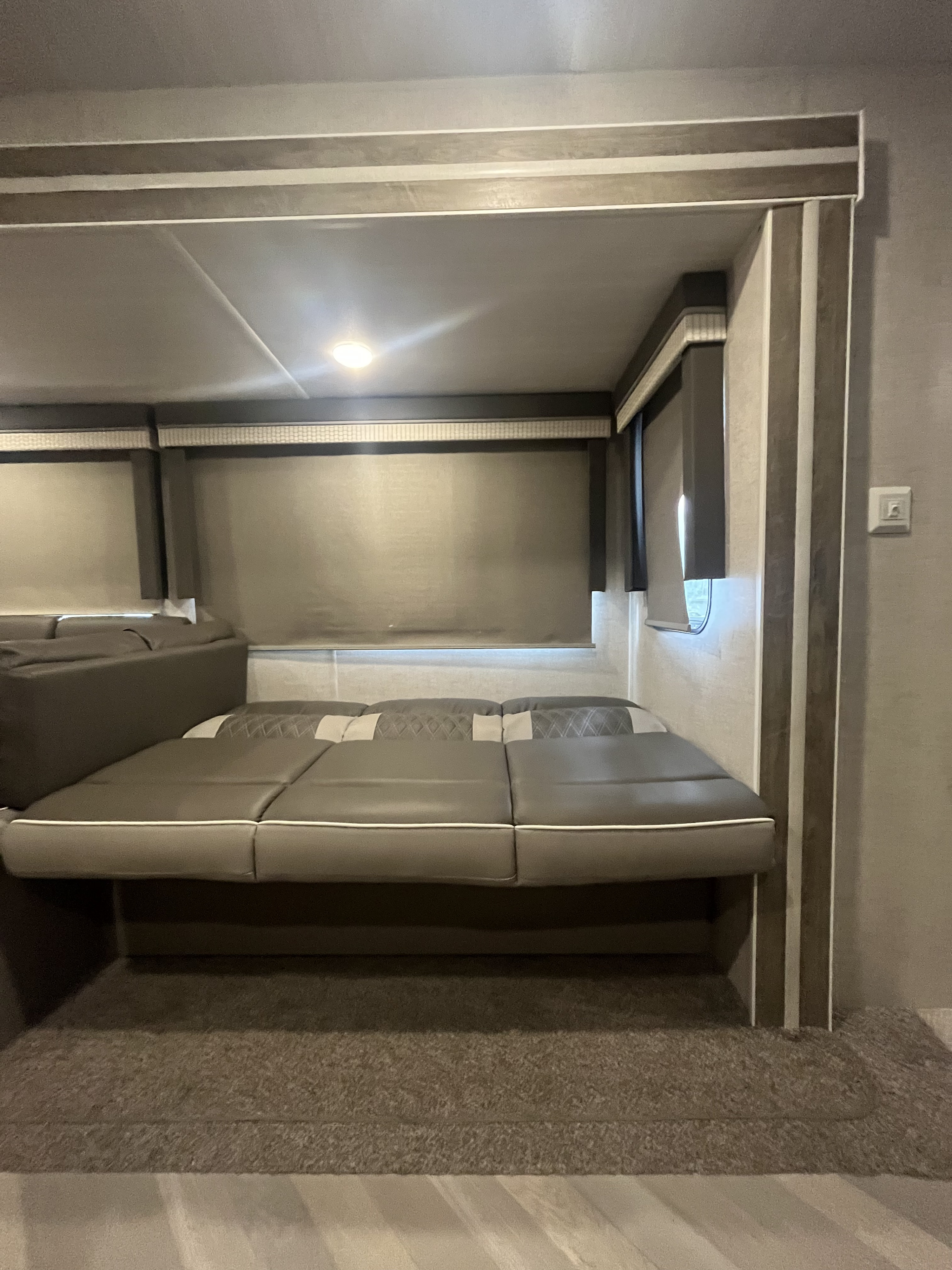 Inside this RV rental, a modern convertible sofa-bed offers comfort in a well-lit space with window shades.. Forest River Salem 2021