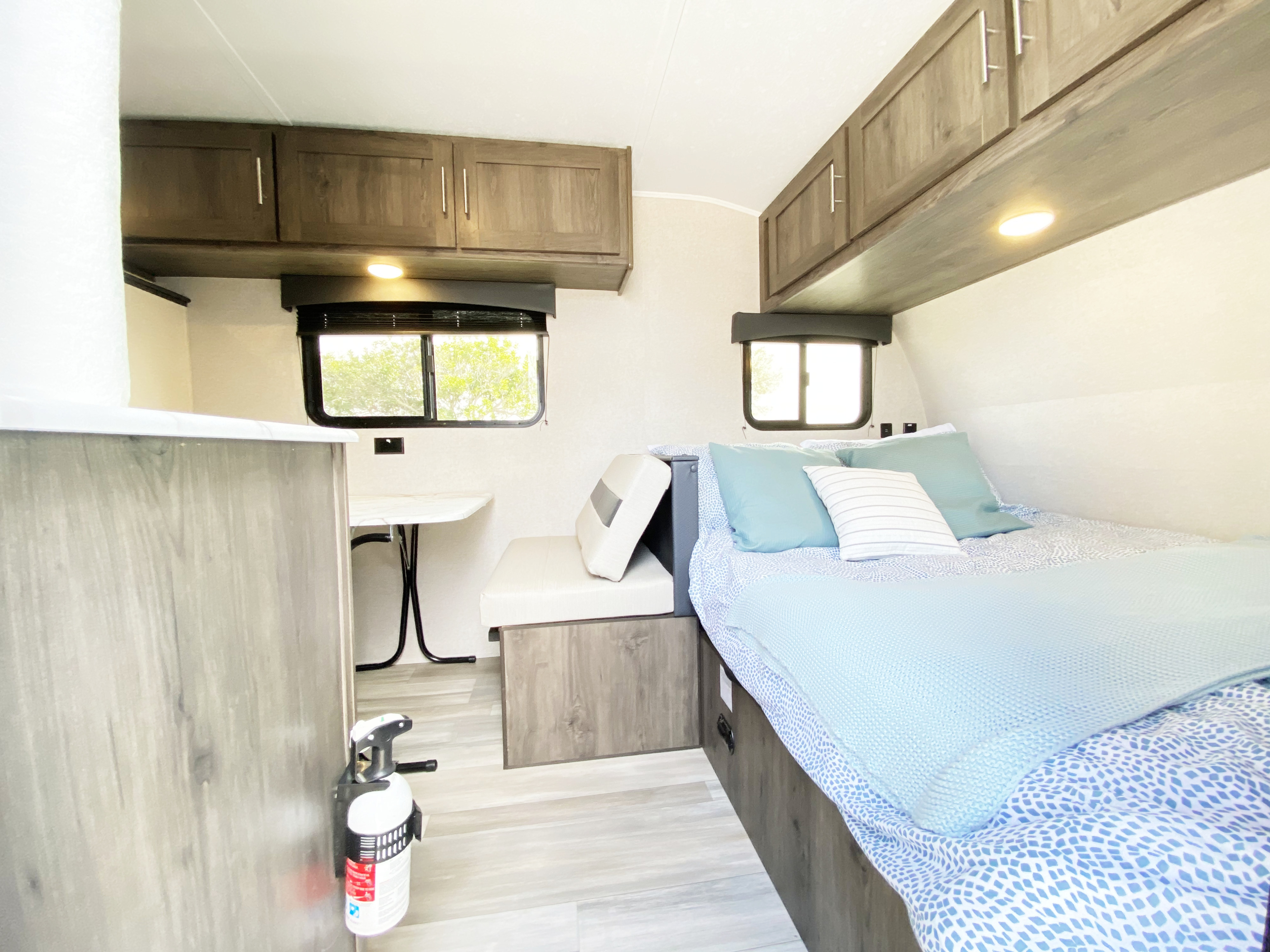 Explore the interior of this RV rental, showcasing a neat bed, convertible dinette, and overhead cabinets.. Forest River Clipper Cadet 2021