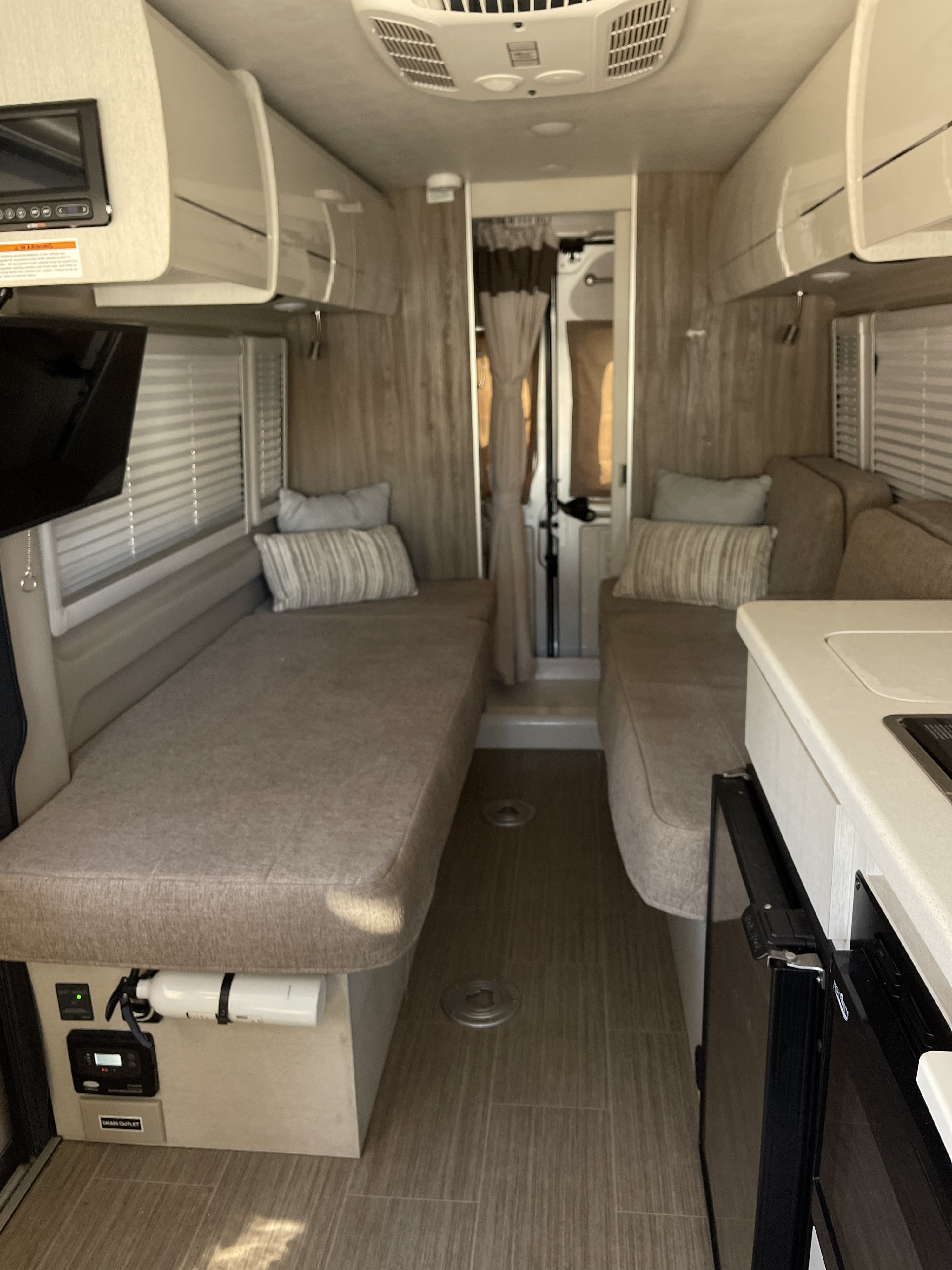Spacious rv rental interior featuring convertible beds, compact kitchen, and overhead storage.. Thor Tellaro 2021