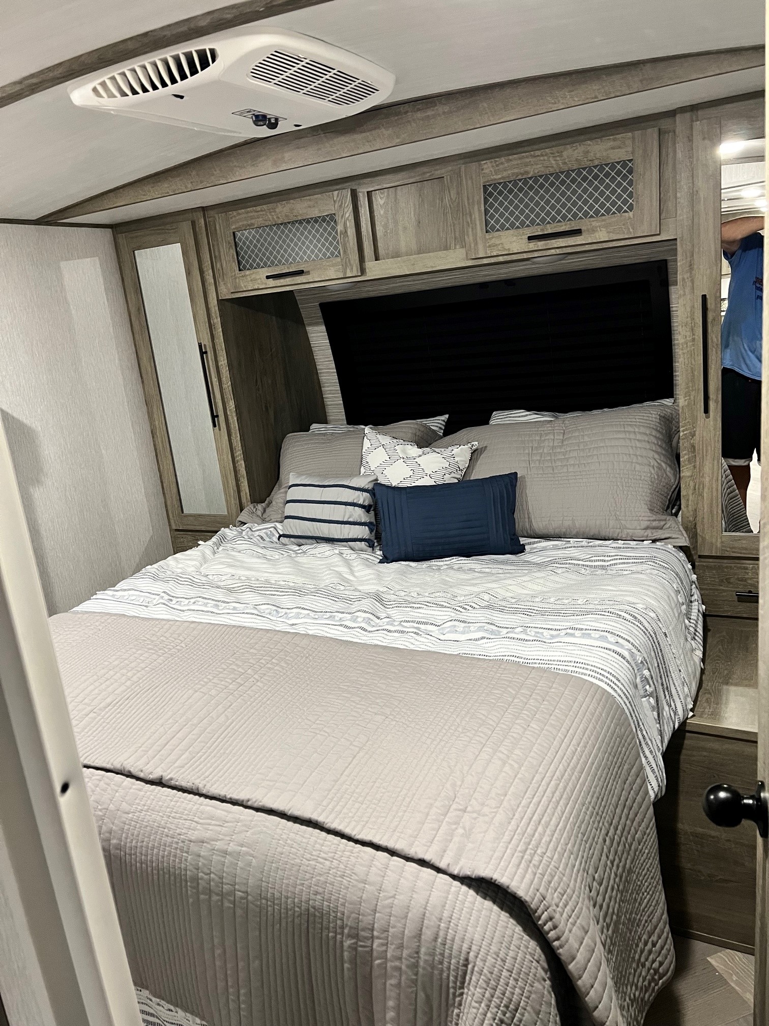 Interior of an RV rental bedroom showing a well-made bed, built-in cabinetry, and ceiling AC unit for comfort.. Forest River Salem Hemisphere 2022