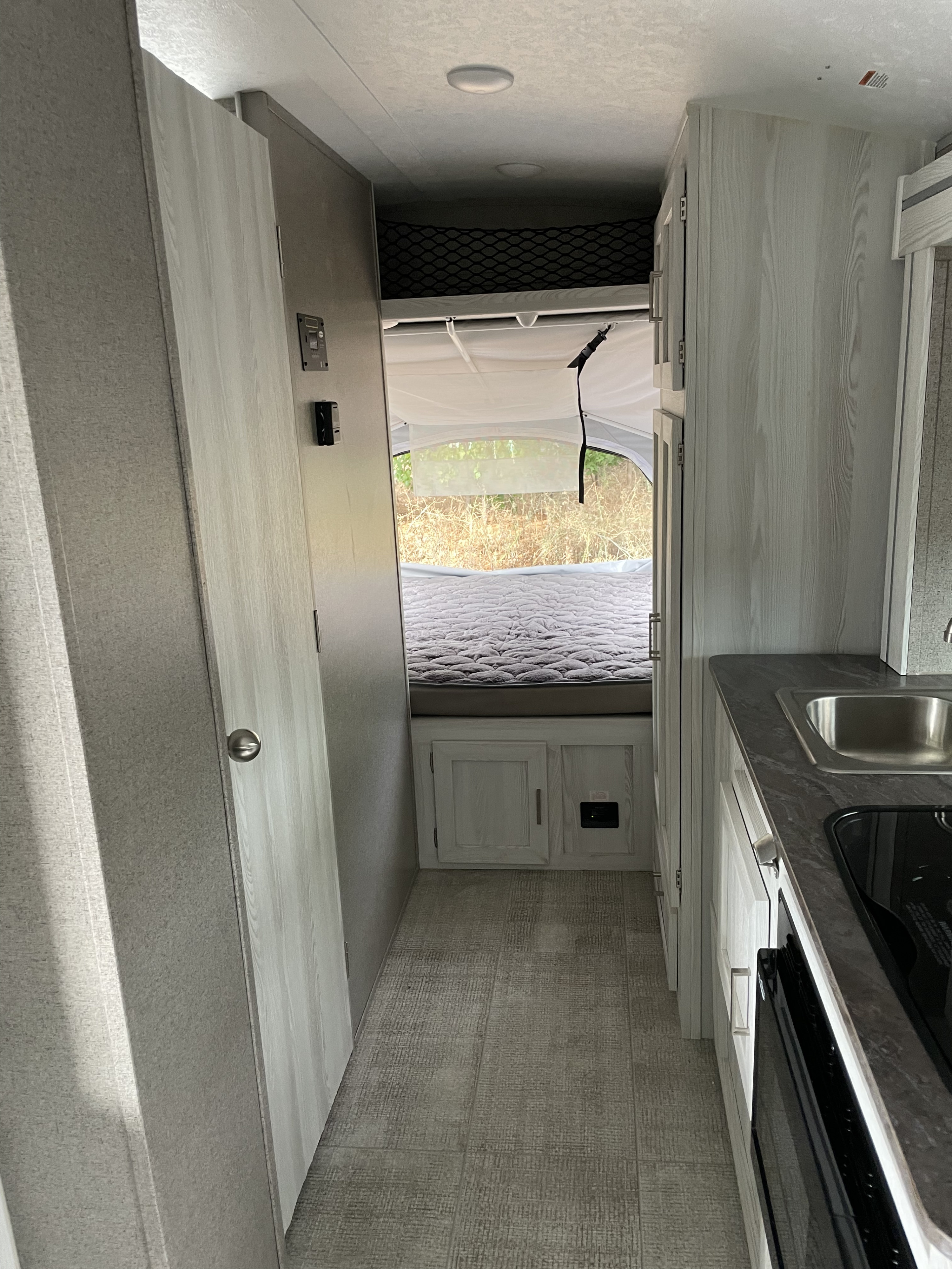 This RV rental's interior shows a bright hallway leading to a pop-out bed area, with a kitchen counter & sink on the right.. Forest River Flagstaff E-Pro 2020