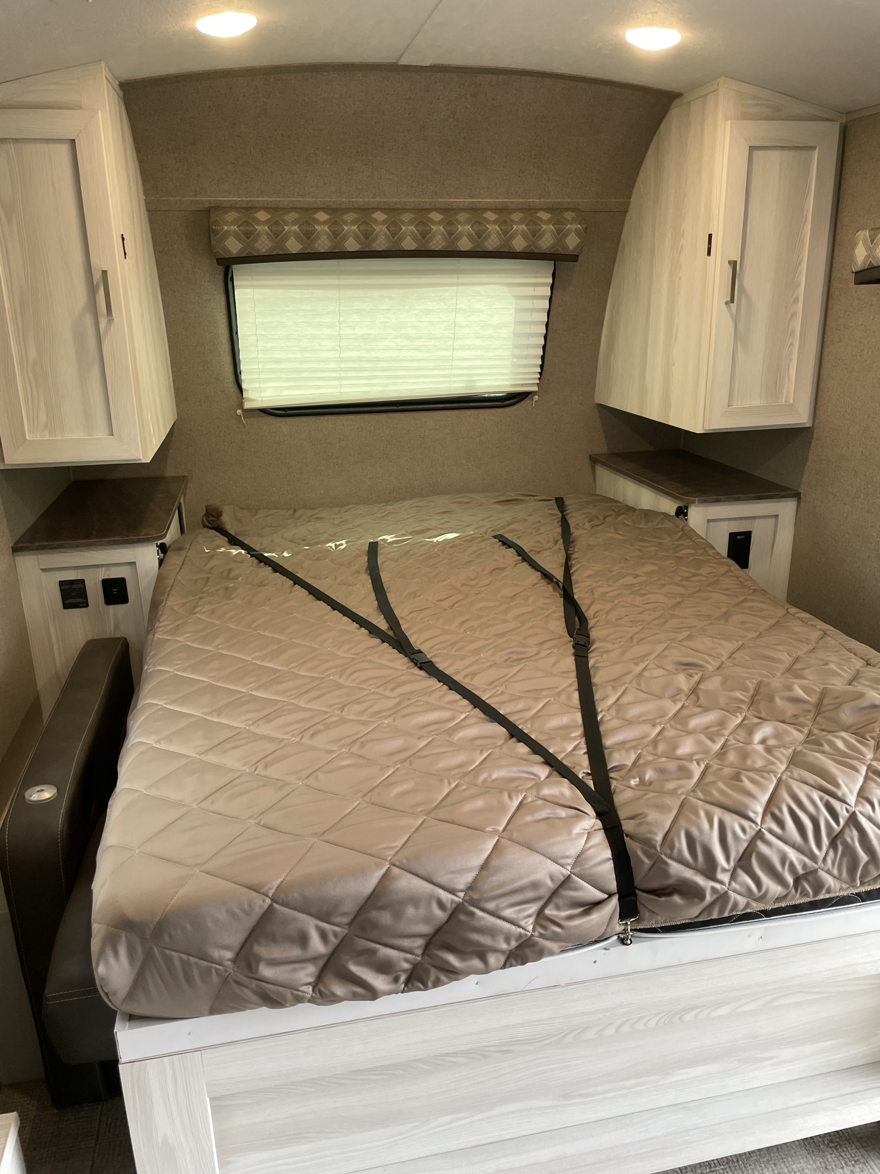 RV rental bedroom: cozy sleeping area with overhead cabinets, nightstands, and secure bed straps. Ideal for travel.. Forest River Flagstaff E-Pro 2020