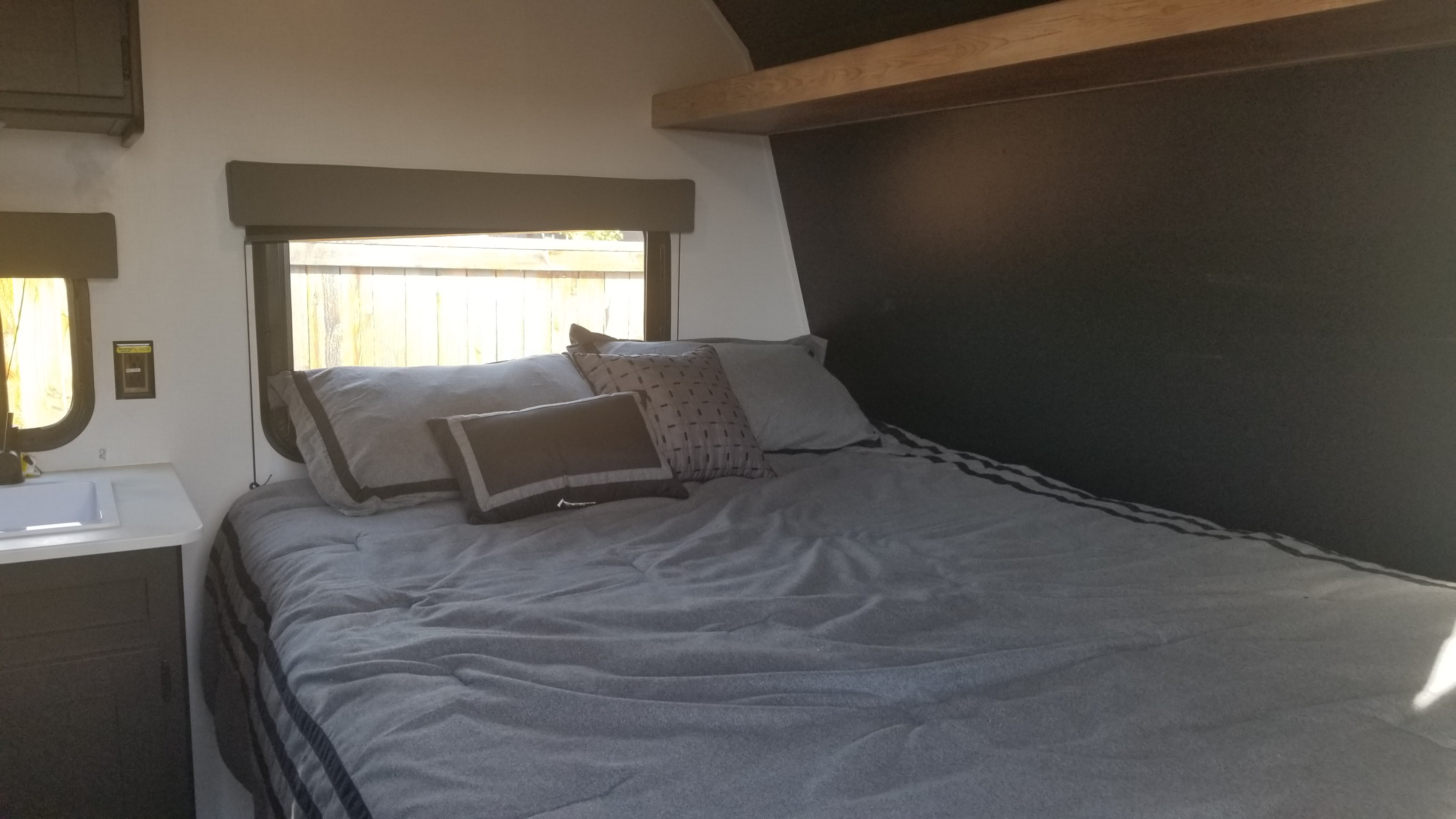 Inviting RV rental bedroom with spacious bed, grey linens, and a counter by bright windows. Perfect for travel.. Keystone RV Springdale 2022