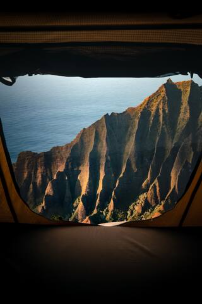 An epic RV rental view: rugged mountains meet the ocean, seen from inside a tent or vehicle opening. Perfect for scenic travel.. Other Other 2021