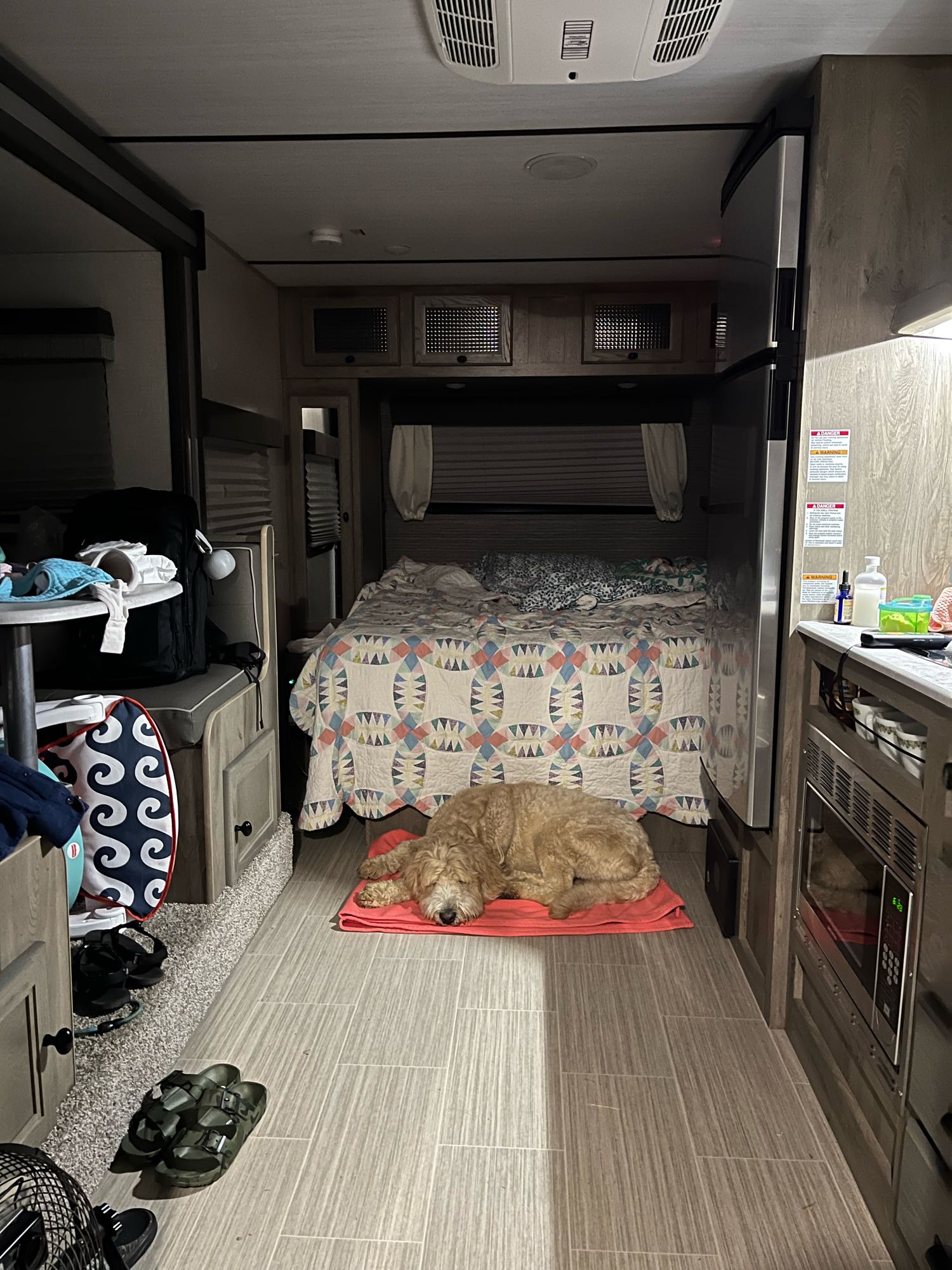 Cozy RV rental interior features a sleeping dog, queen bed, full kitchen, and dining area, ideal for travel.. Forest River Surveyor 2021