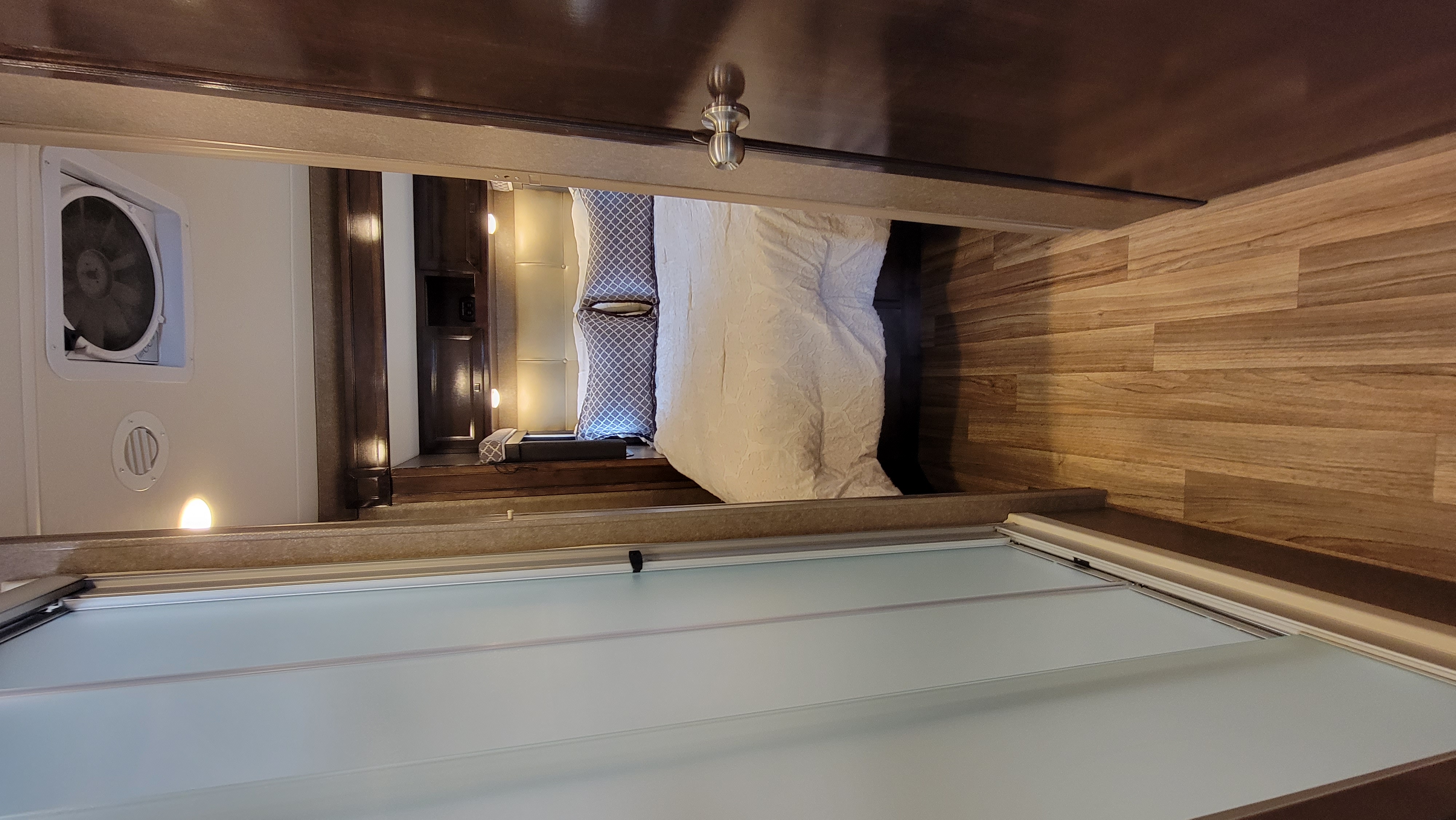 RV rental bedroom showcasing a comfortable bed, ceiling fan, and frosted sliding door.. Thor Synergy 2019