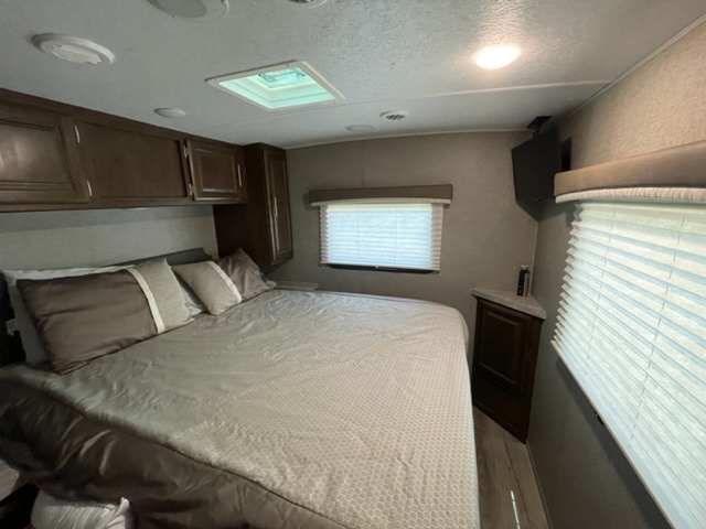 Enjoy this cozy RV rental bedroom featuring a bed, skylight, mounted TV, and ample storage cabinets.. Forest River Flagstaff Micro Lite 2021