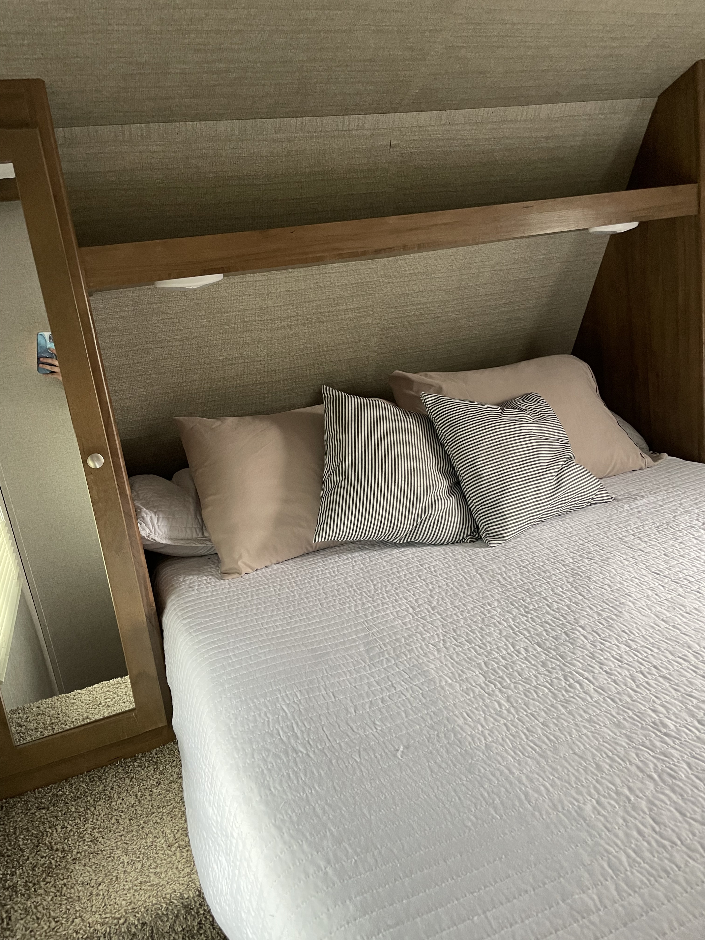 Compact RV rental bedroom with a cozy bed, white quilted comforter, and patterned pillows.. Dutchmen Aspen Trail 2790BHS 2019