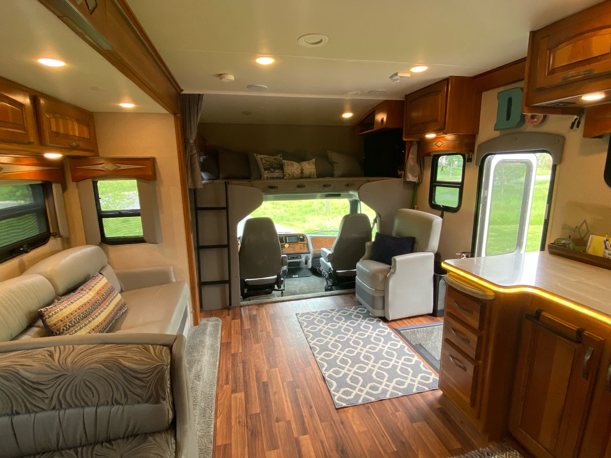 Spacious rv rental interior: living area, kitchen, and overhead bunk with warm lighting on hardwood floors.. Jayco Seneca 2016