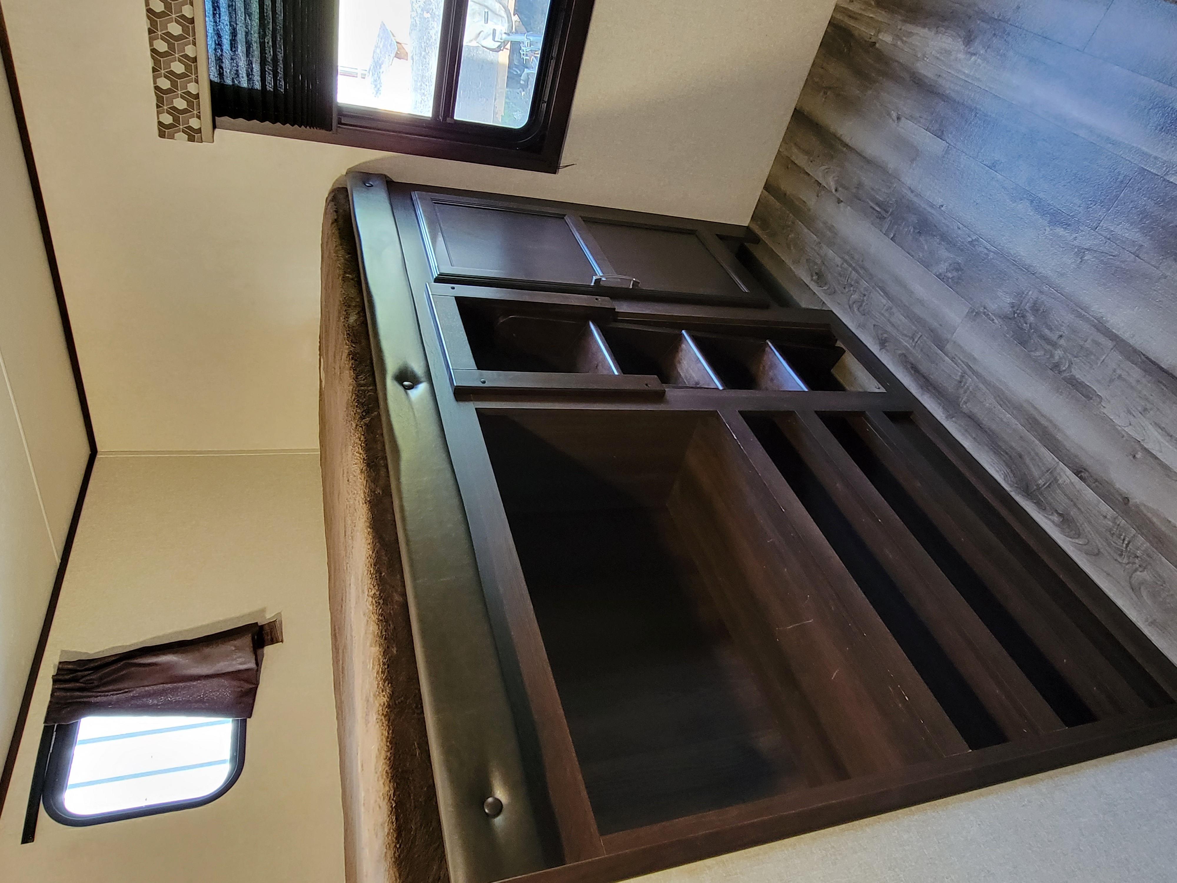 RV rental bedroom interior: dark wood bed frame with integrated storage shelves, window, and wood-look flooring.. Jayco Jay Flight 2020
