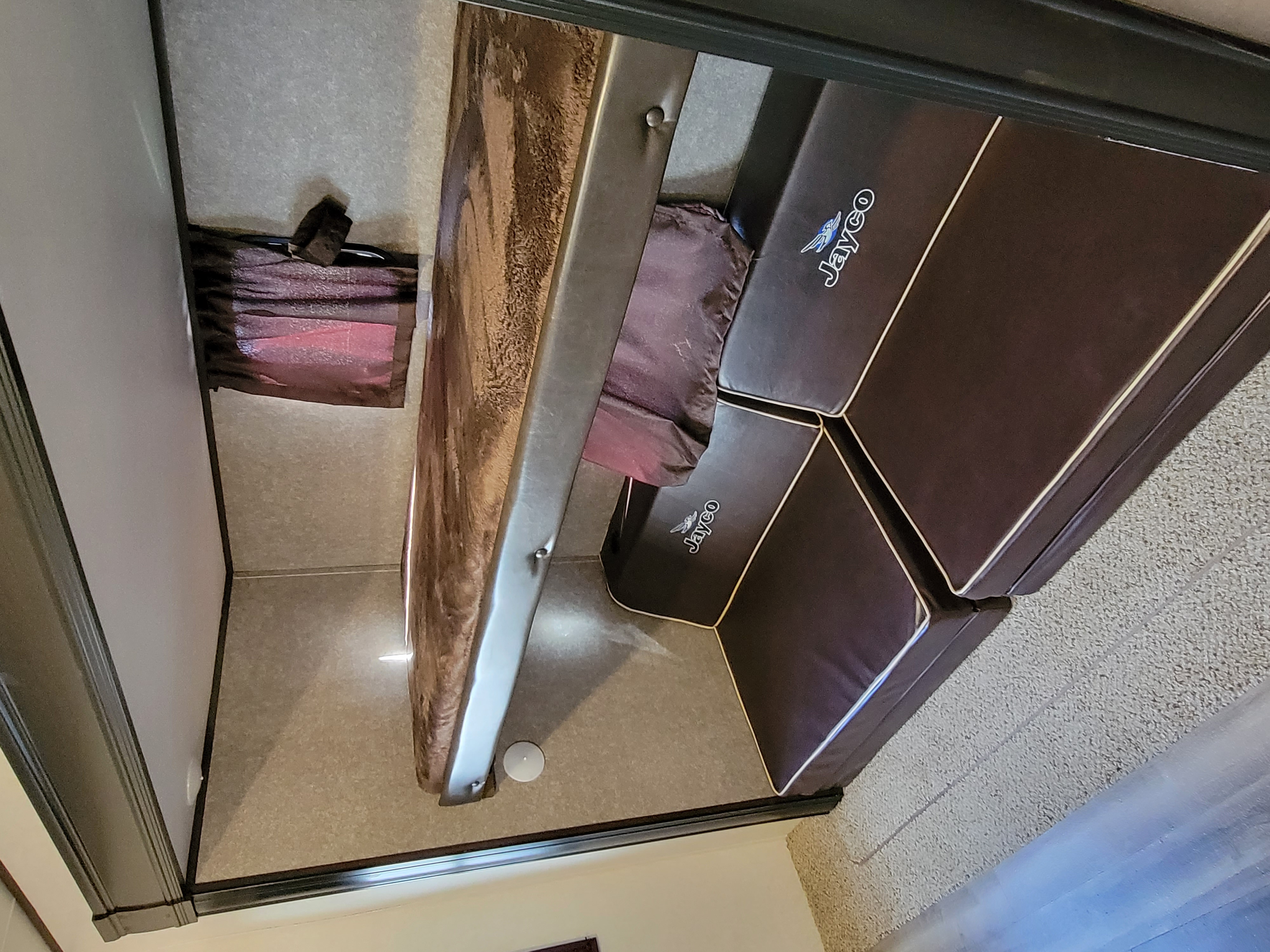 Inside an RV rental, a brown bunk bed and dark Jayco sofa with white piping create a cozy sleeping/living space.. Jayco Jay Flight 2020