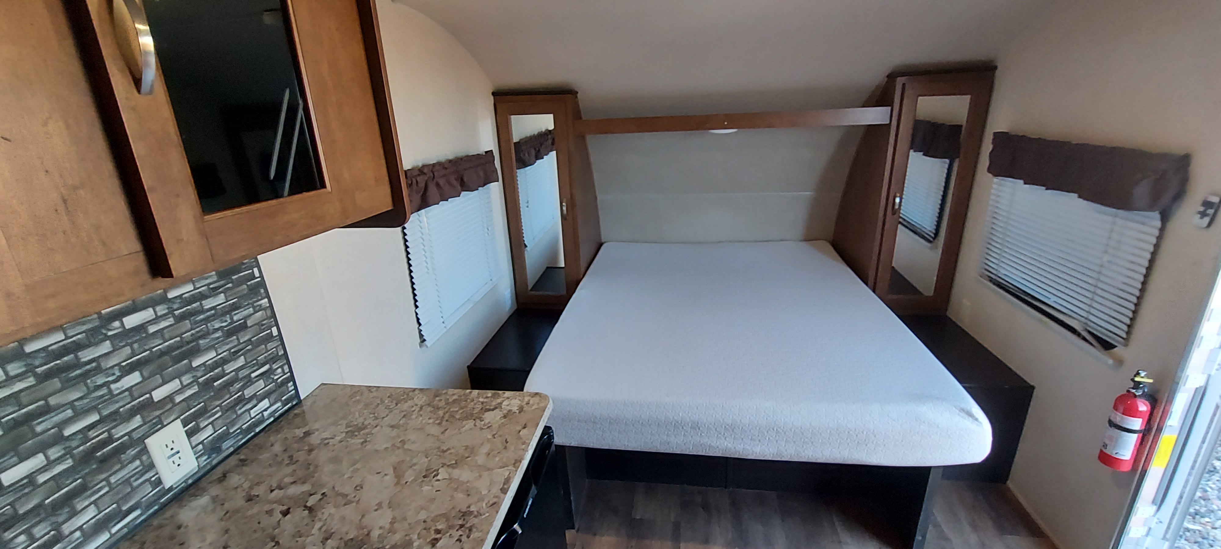 Inside an RV rental: Compact interior with a cozy bed, mirrored cabinets, kitchen counter with outlet, and fire extinguisher.. Forest River Salem Cruise Lite 2017