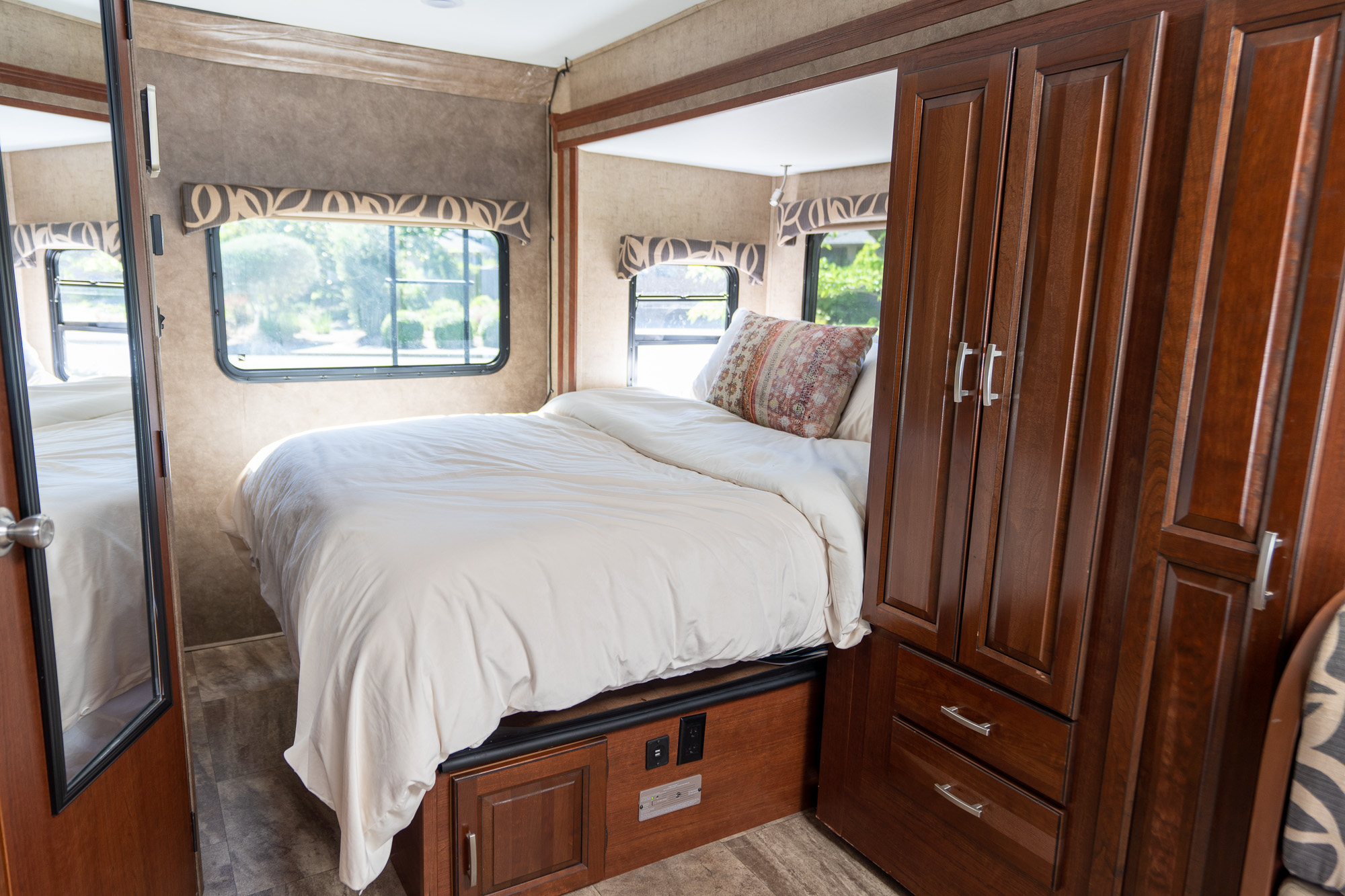 Cozy RV rental bedroom featuring a comfortable bed, large windows for natural light, and built-in wood storage cabinets.. Forest River Forester 2401W 2016