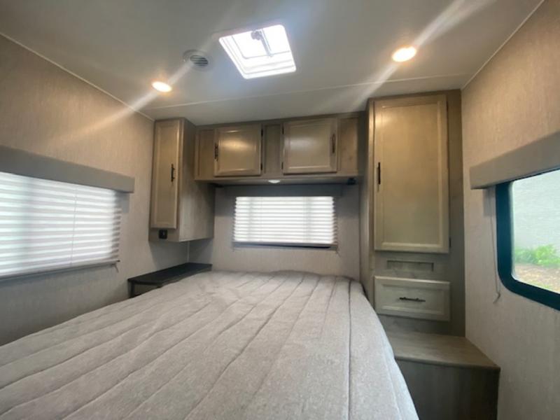 Cozy RV rental bedroom featuring a large bed, ample storage cabinets, and bright windows with blinds.. Forest River Coachmen Freelander 2022