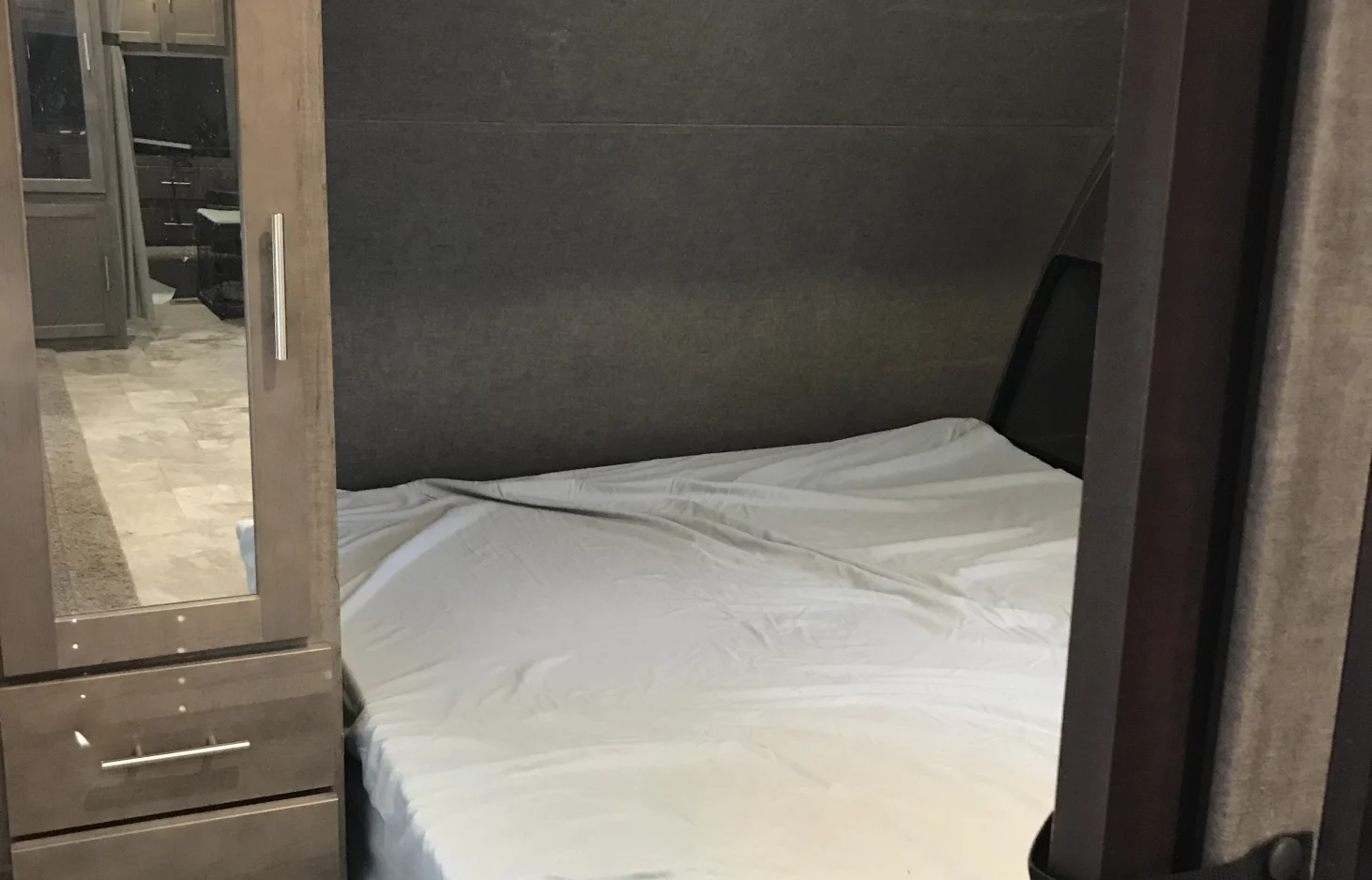 Inside an RV rental: a compact bedroom featuring a comfortable bed, mirrored closet, and dark interior. Sleep soundly on the go.. Forest River Surveyor 2017