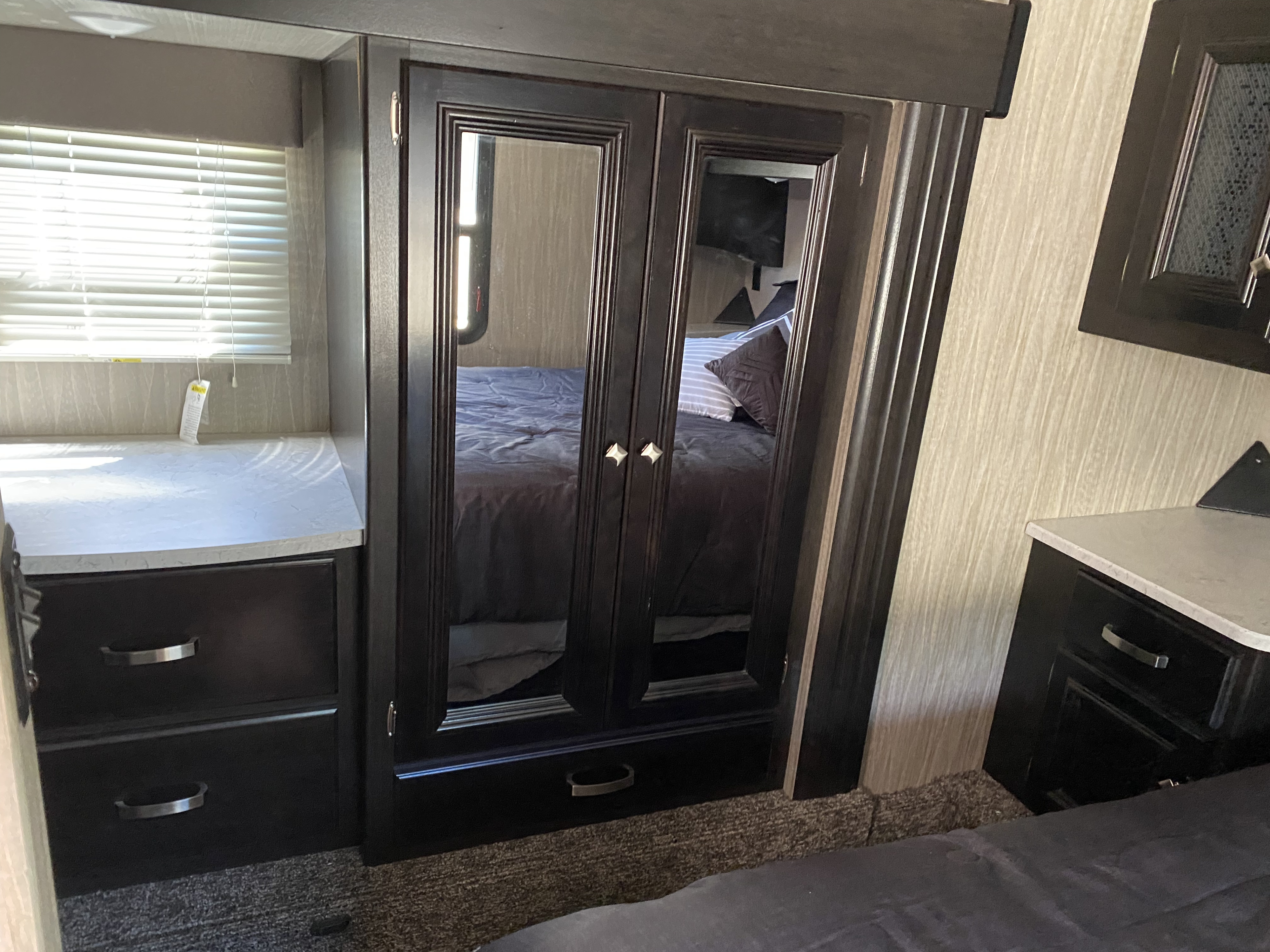 Spacious RV rental bedroom featuring a mirrored wardrobe, storage drawers, and window blinds for comfort.. Heartland Other 2019