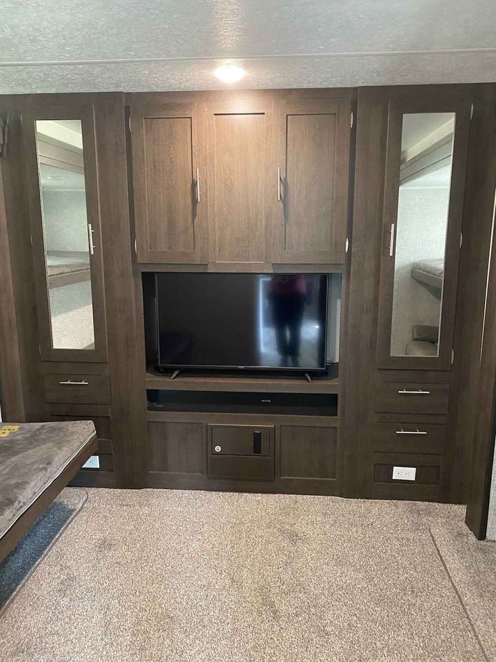 This RV rental bunkhouse features a central TV, extensive wood storage, and mirrored closets reflecting twin bunk beds.. Forest River Salem 2020