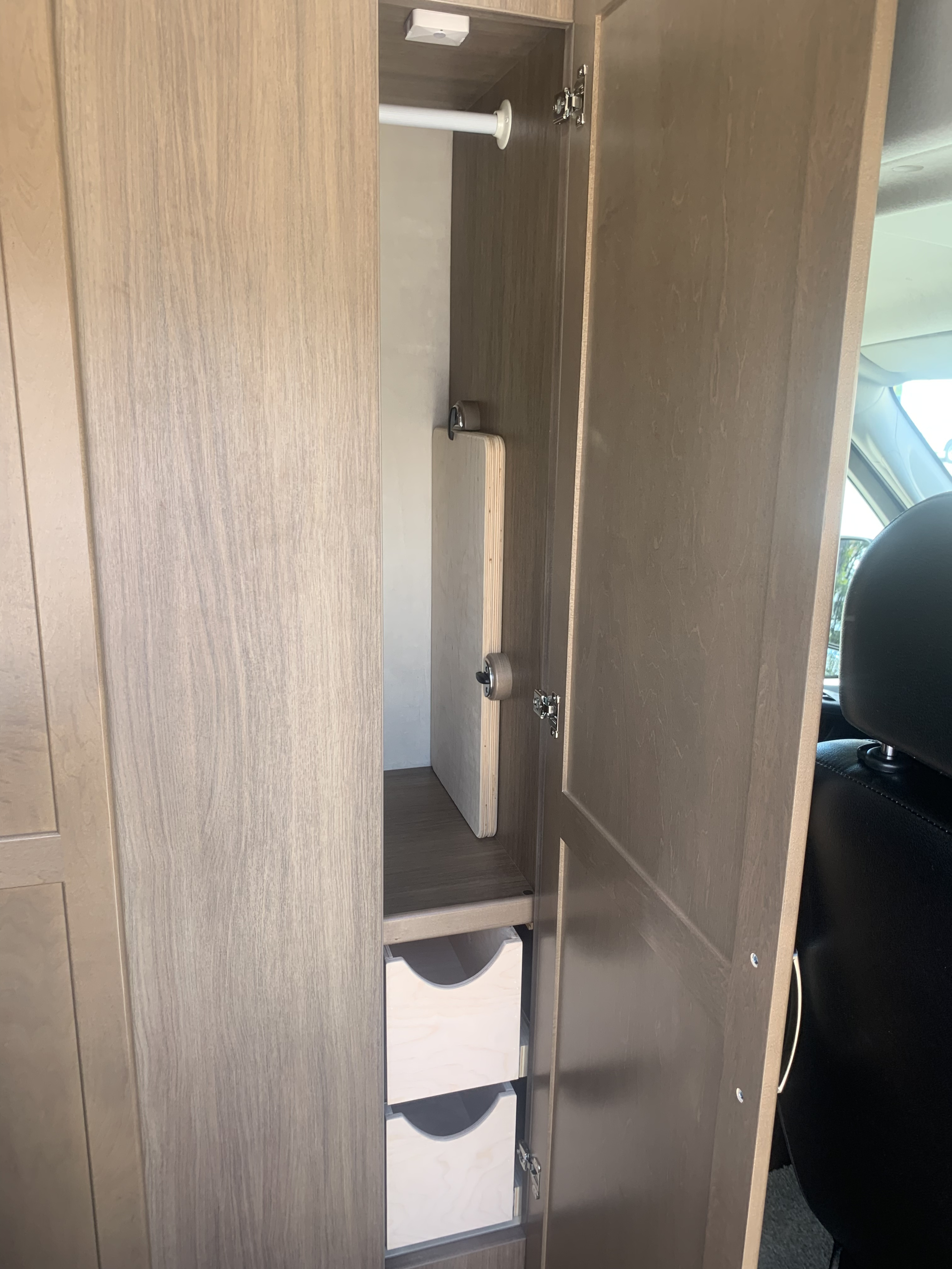 Inside an RV rental: a versatile cabinet with hanging rod, stowed table, and pull-out drawers for smart storage solutions.. Pleasure-Way Pleasure-Way Class B 2020