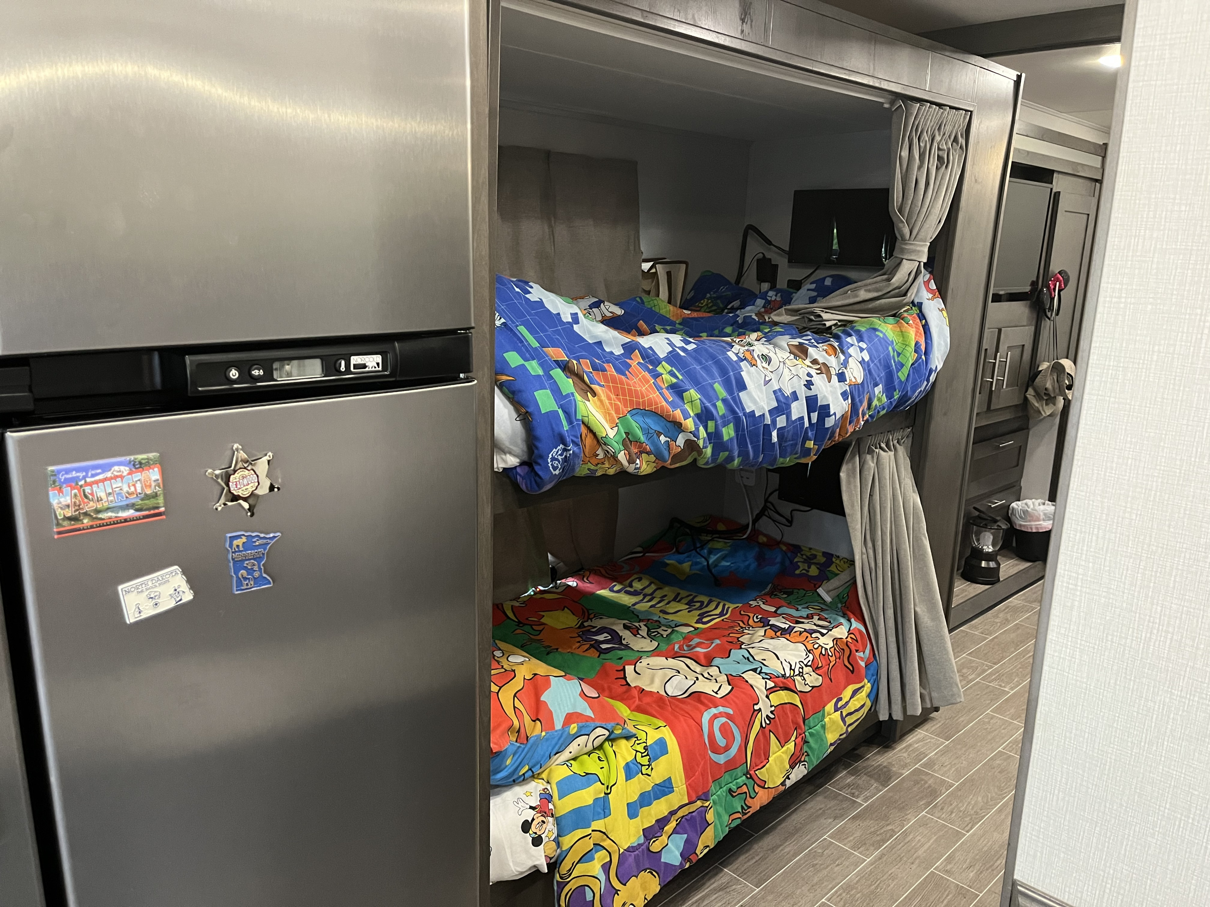 Cozy RV rental interior features colorful bunk beds, a stainless steel refrigerator with magnets, and privacy curtains.. Forest River Georgetown 2022