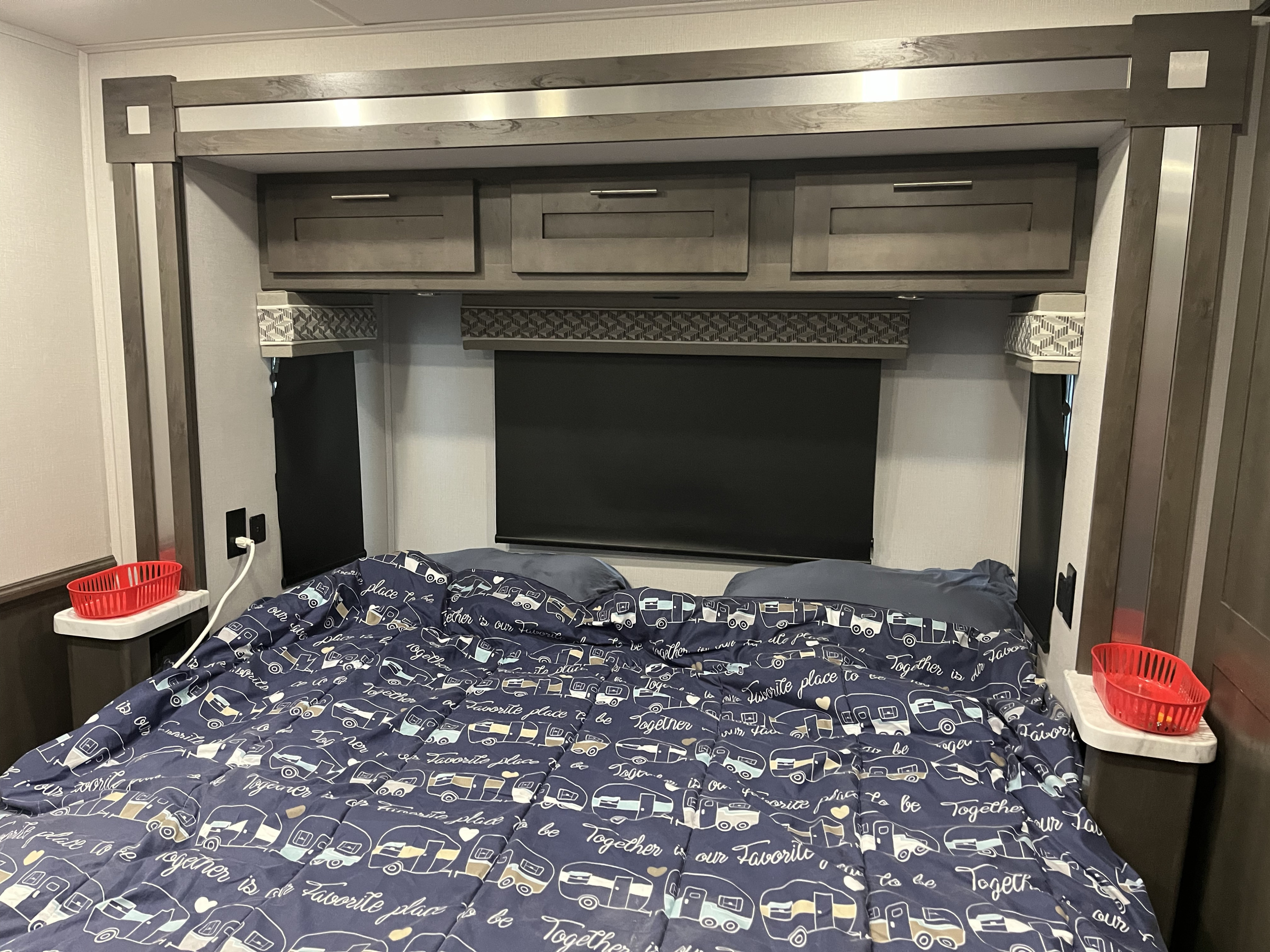 RV rental bedroom interior: compact space with camper-print bedding, built-in storage, side tables, and practical design.. Forest River Georgetown 2022
