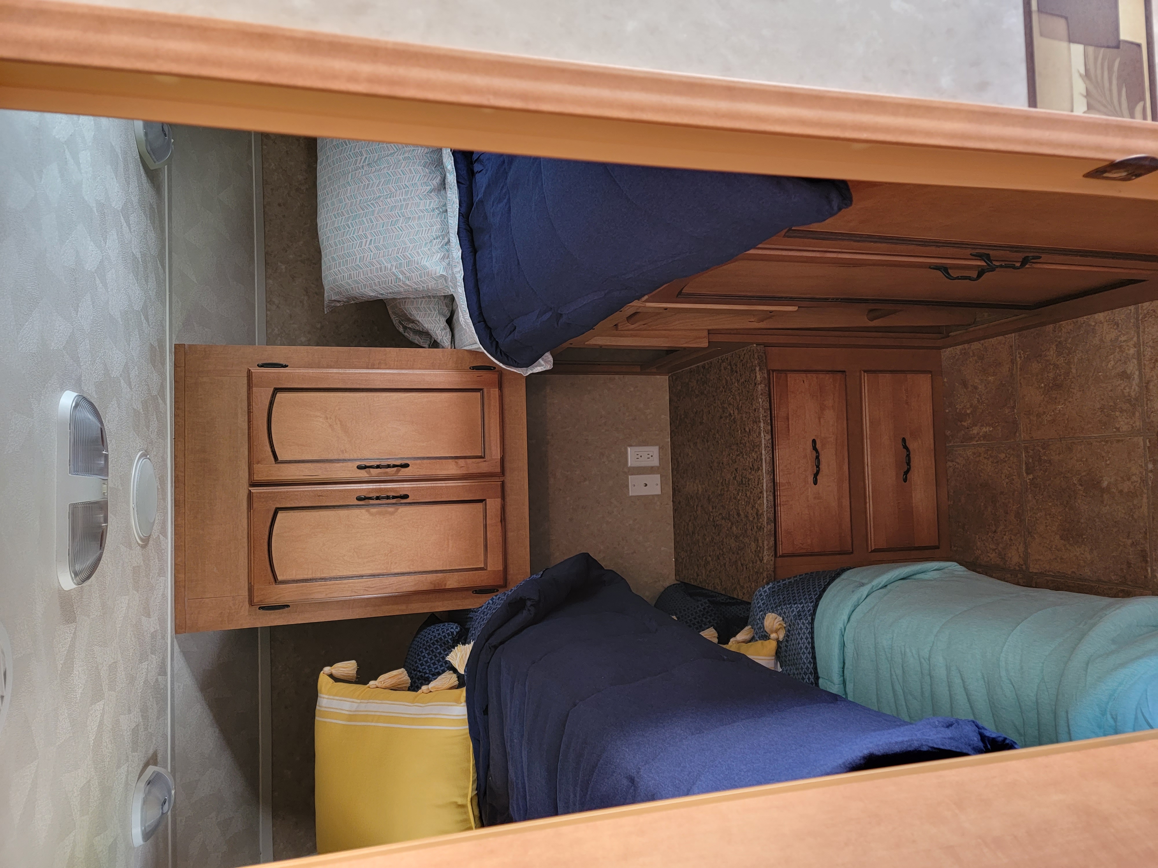This RV rental features comfortable bunk beds with varied bedding, wooden storage, and textured walls, offering a cozy sleep area.. Forest River Palomino Puma 2011